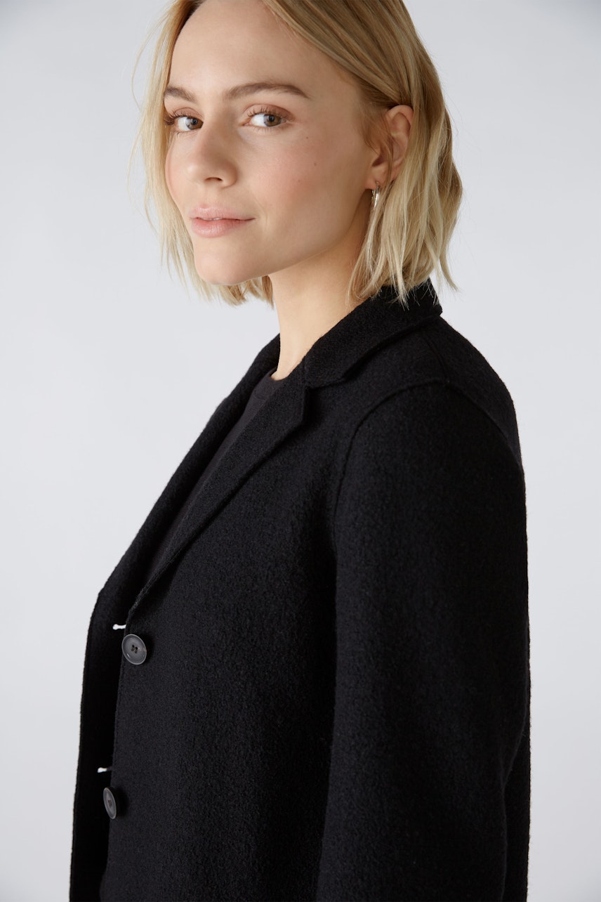 Elegant women's coat: A woman in a stylish black coat with buttons, exuding sophistication.