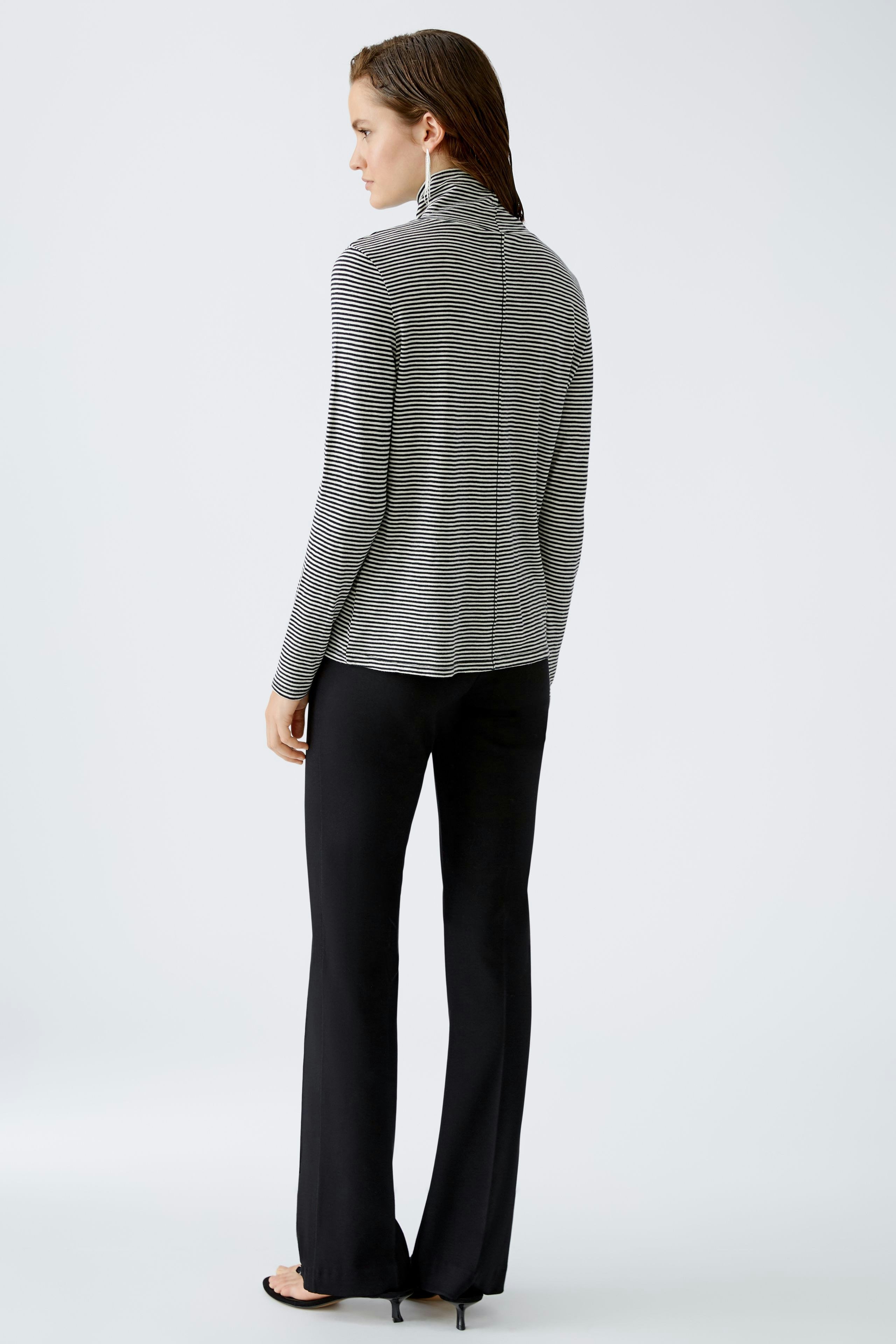 Eleganter Damen-Pullover: Frau in gestreiftem Pullover mit Stehkragen und schmalen Hosen.