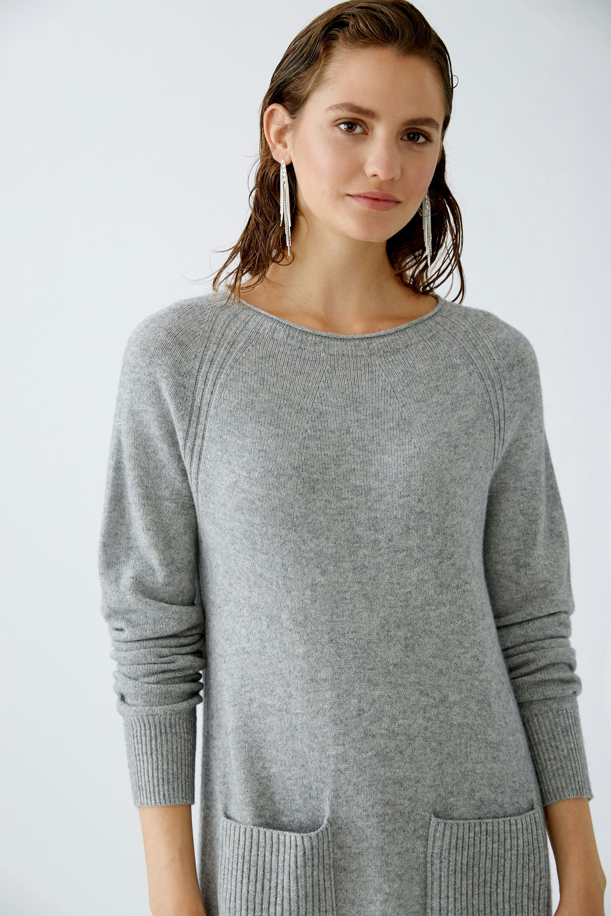 Eleganter Damen-Pullover: Frau in grauem, weichem Strickpullover mit praktischen Taschen.