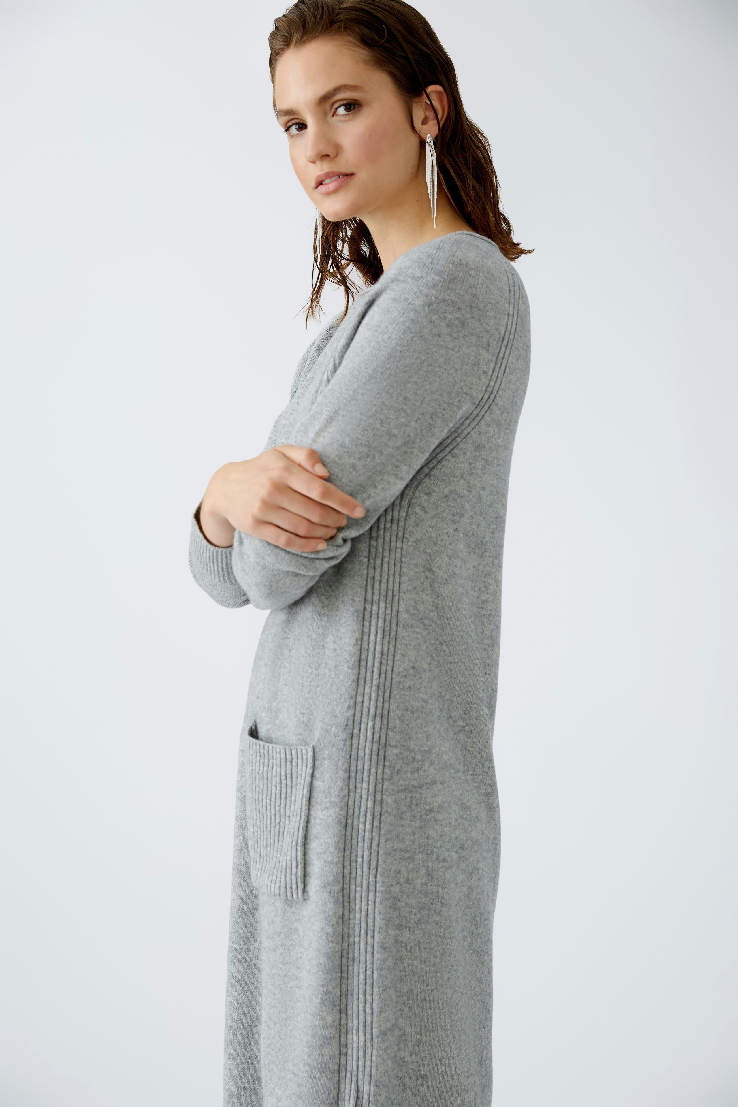 Elegantes Damen-Kleid: Frau in grauem, langem Kleid mit praktischer Tasche und modernem Design.