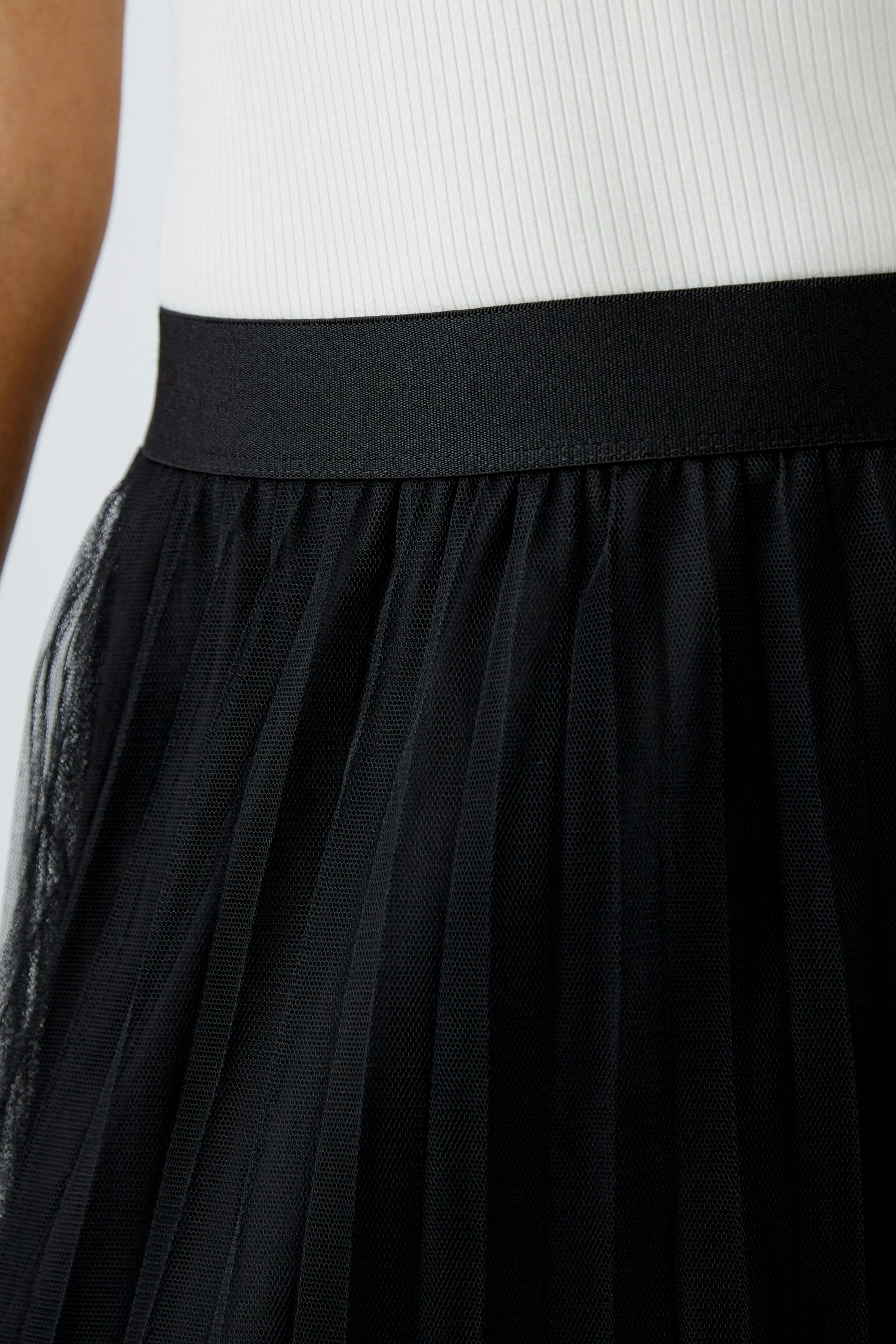 Elegant midi skirt: Close-up of a woman's black pleated skirt with a smooth waistband.