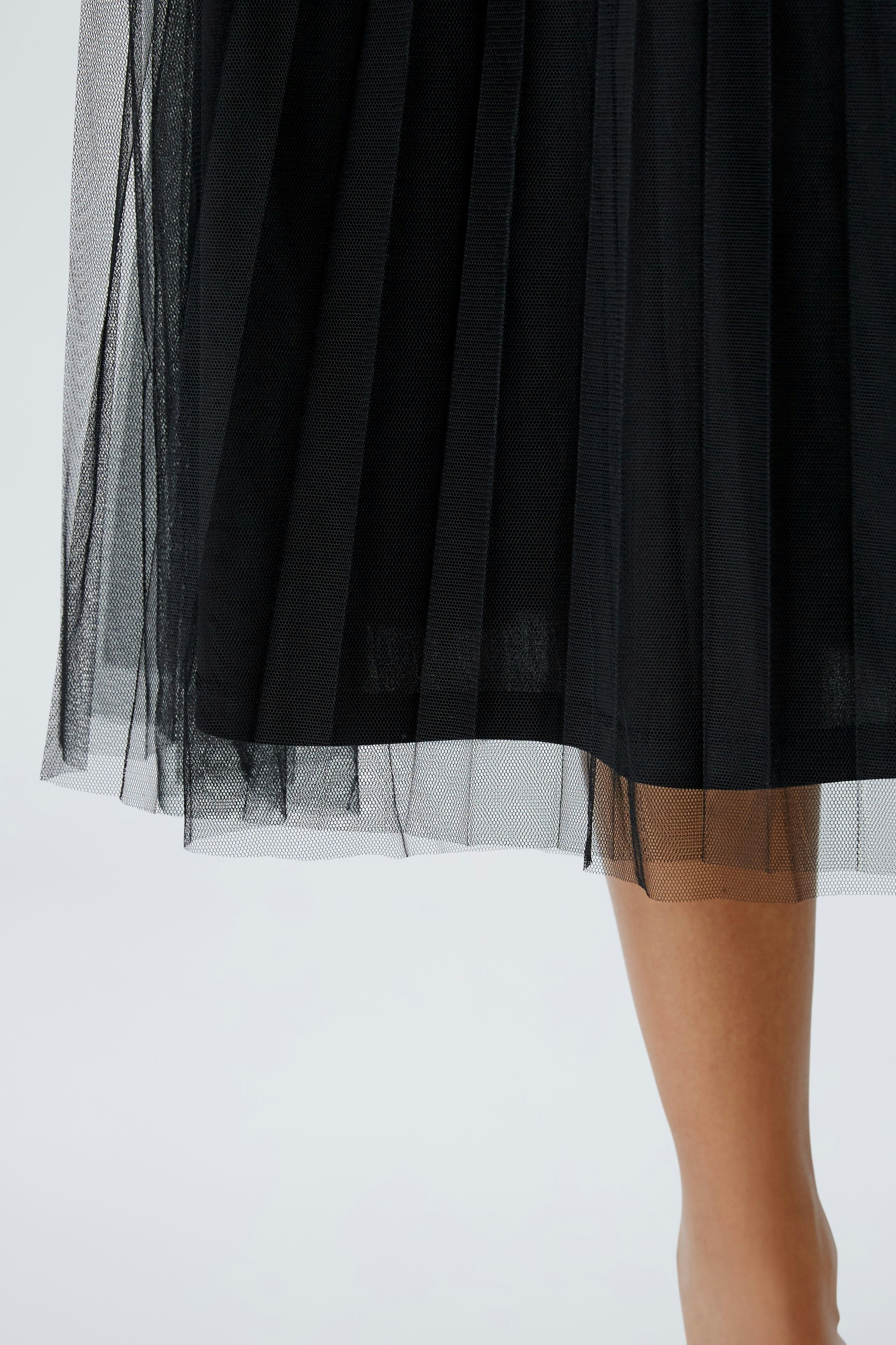 Elegant midi skirt: A woman showcases a flowing black pleated skirt, perfect for any occasion.