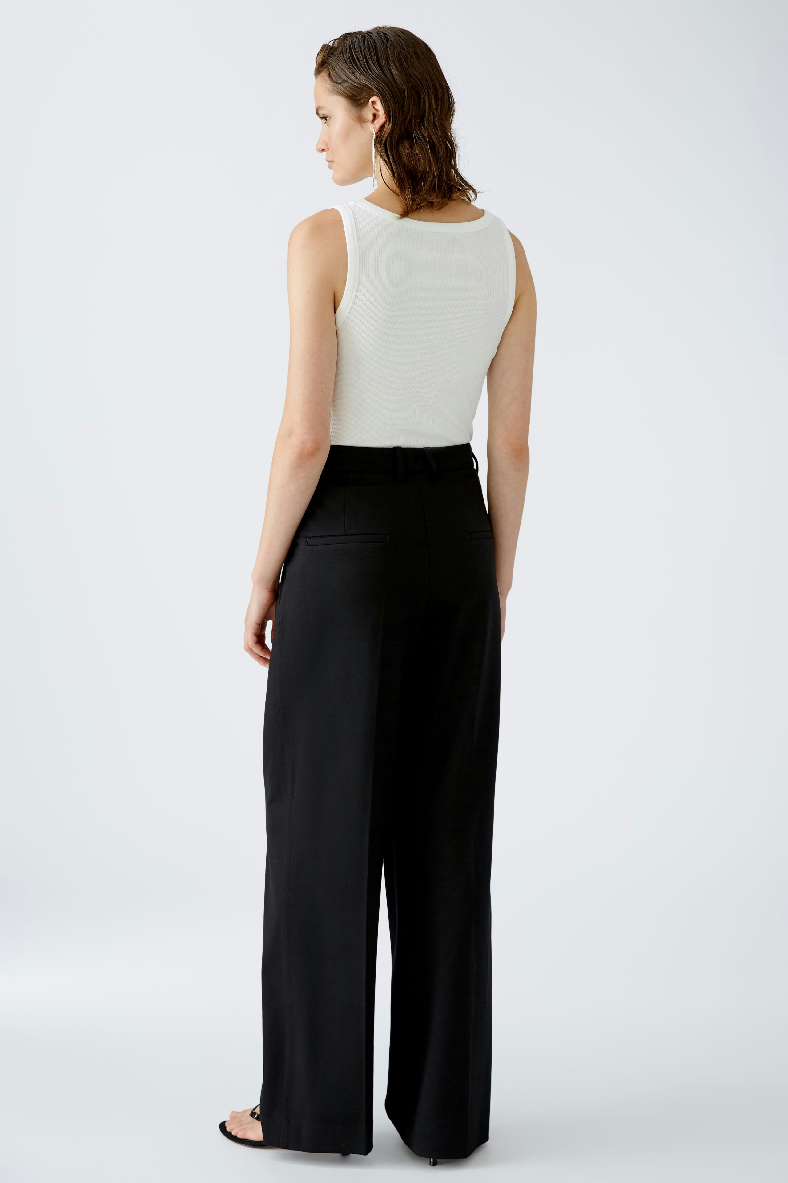 Chic women's pleated trousers: A woman in black trousers with a sleek design, showcasing modern elegance.