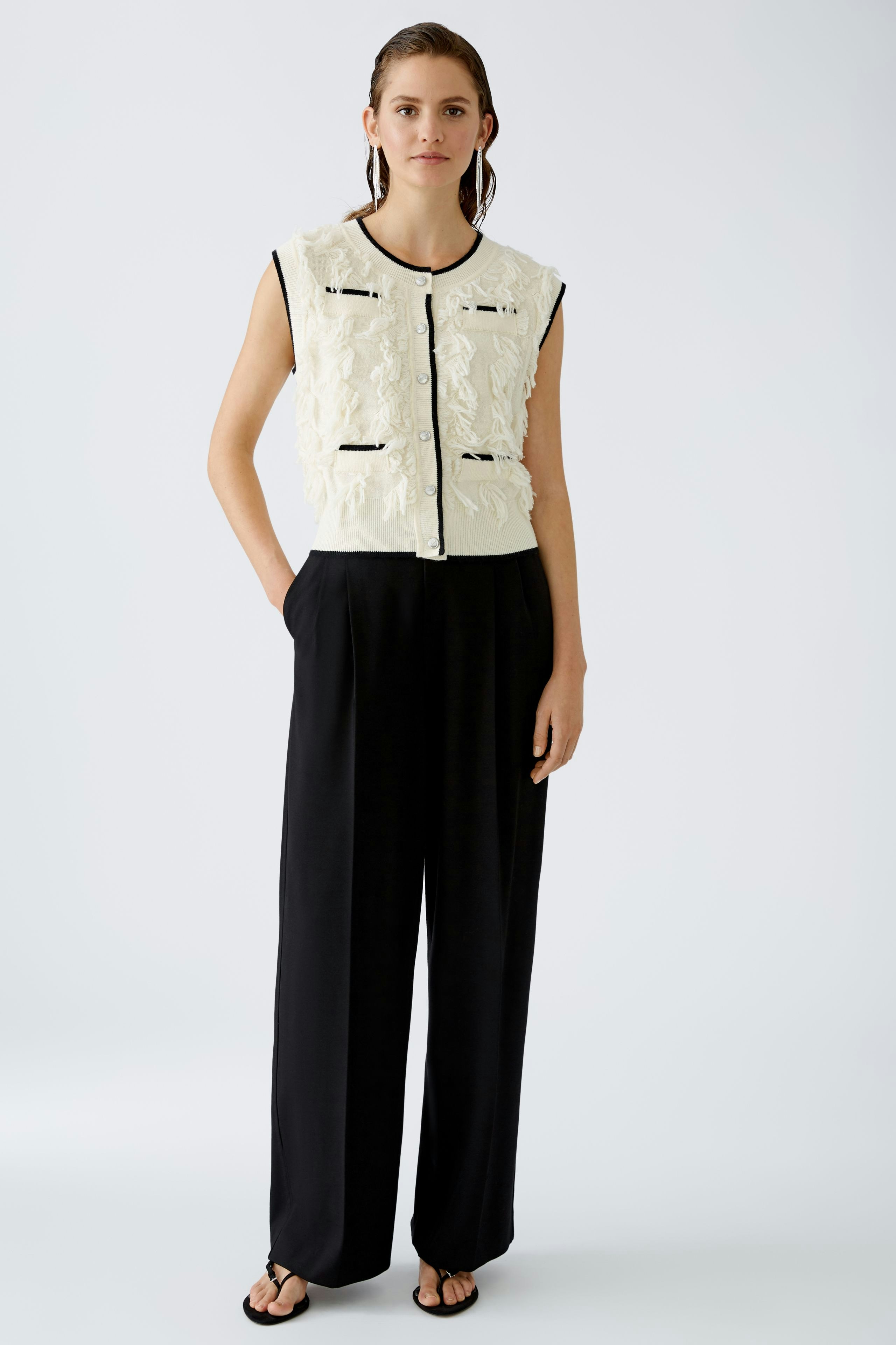 Elegant women's pleated trousers: A woman in stylish black trousers stands confidently.
