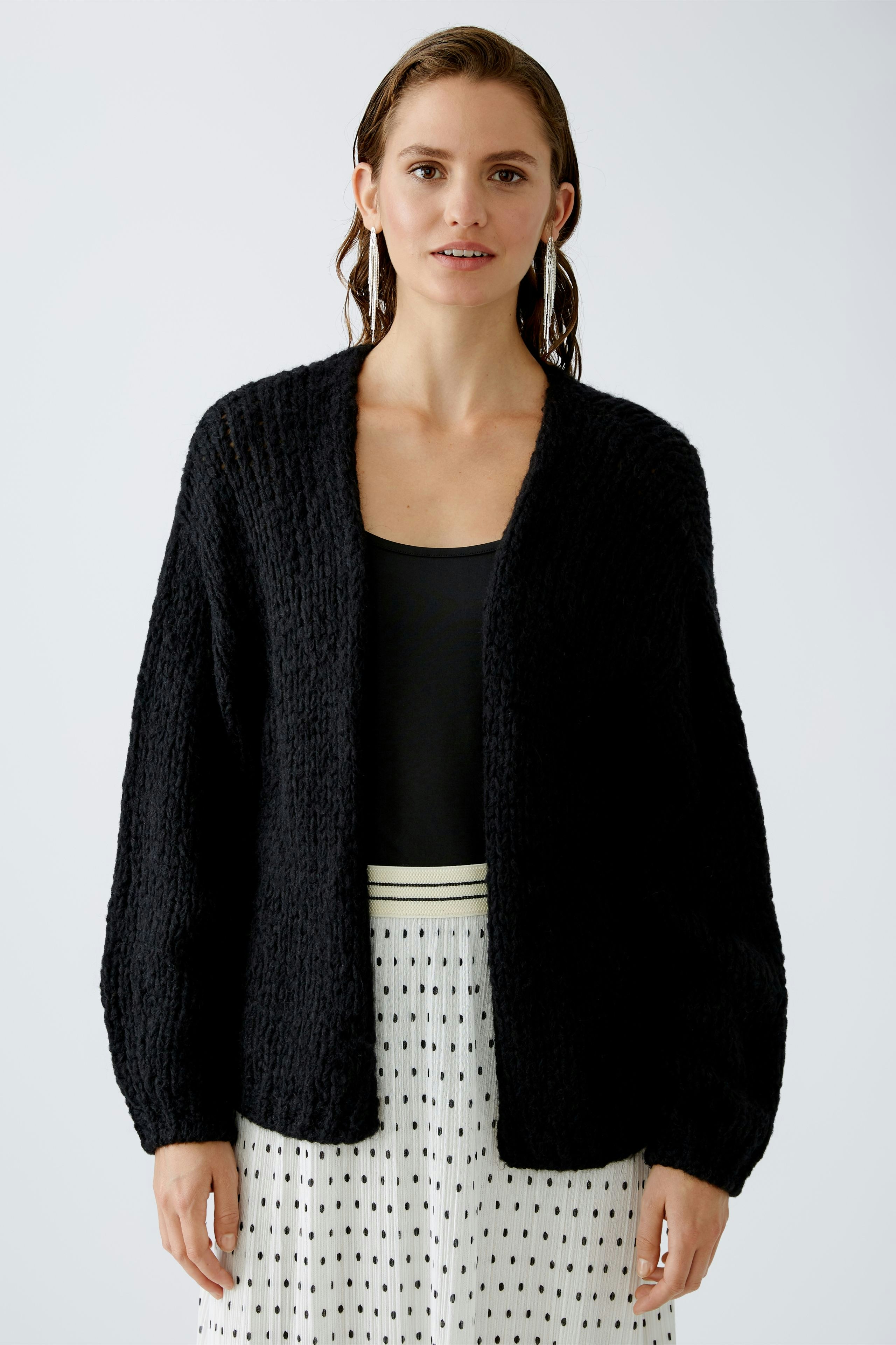 Schlichte Damen-Strickjacke: Frau in schwarzer Strickjacke mit lässigem Schnitt und elegantem Look.