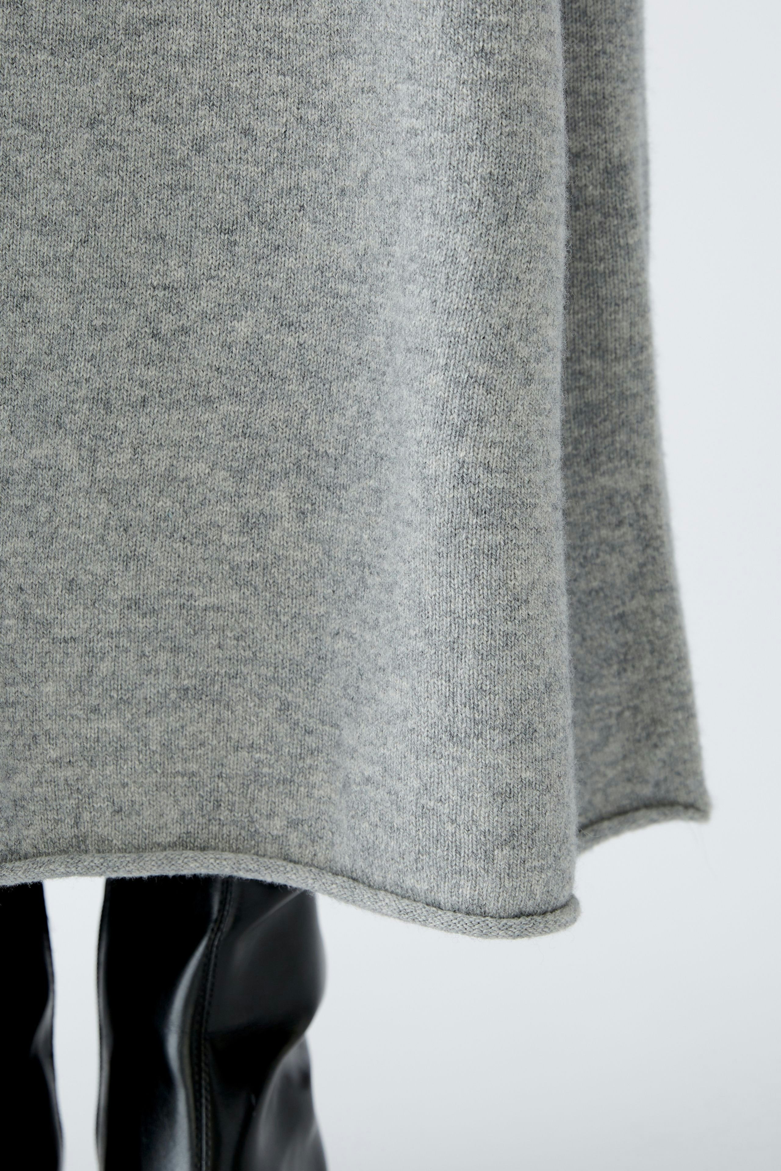 Eleganter A-Linien-Rock: Frau trägt einen grauen Rock, der sanft um die Beine fällt.