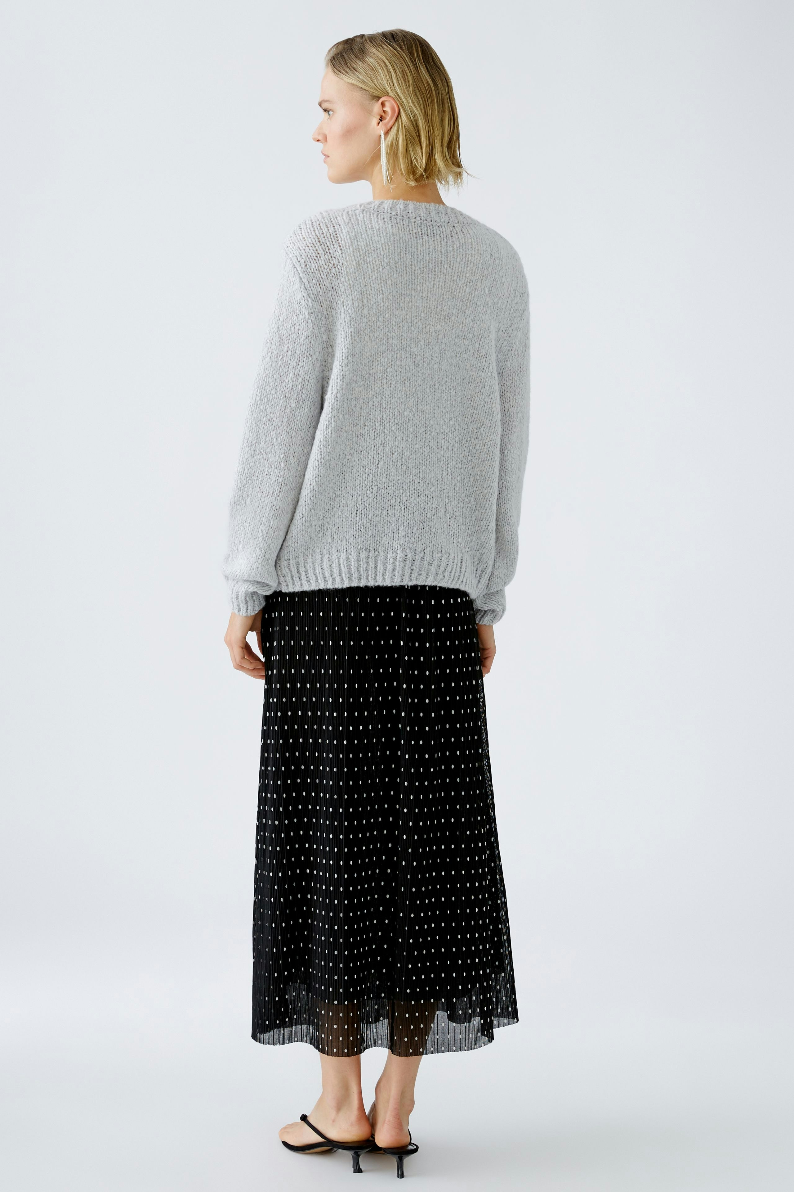 Stylish women's pullover: A woman in a cozy gray pullover paired with a flowing black skirt.
