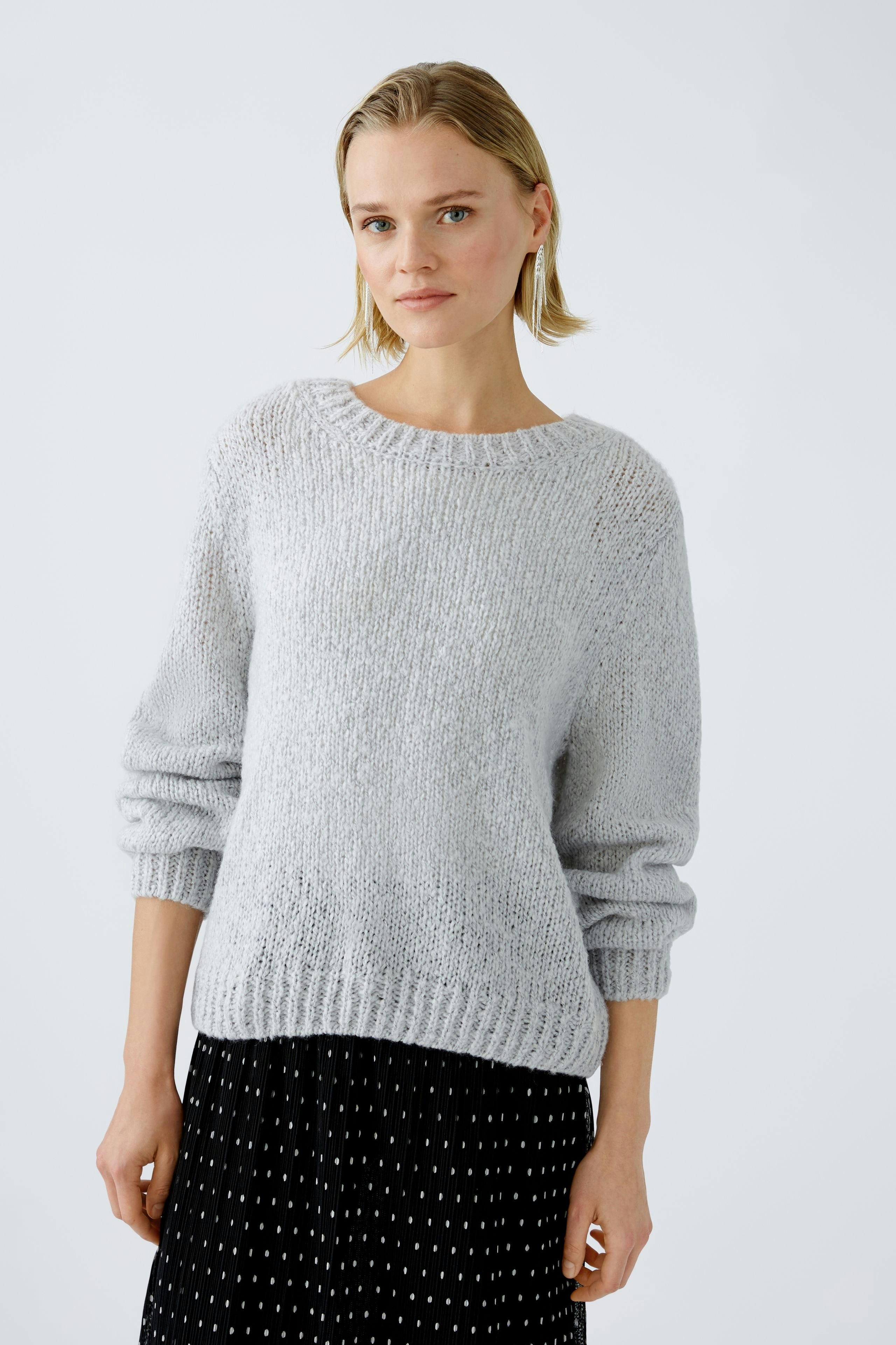 Modern women's pullover: A woman in a light gray pullover with relaxed fit and stylish design.