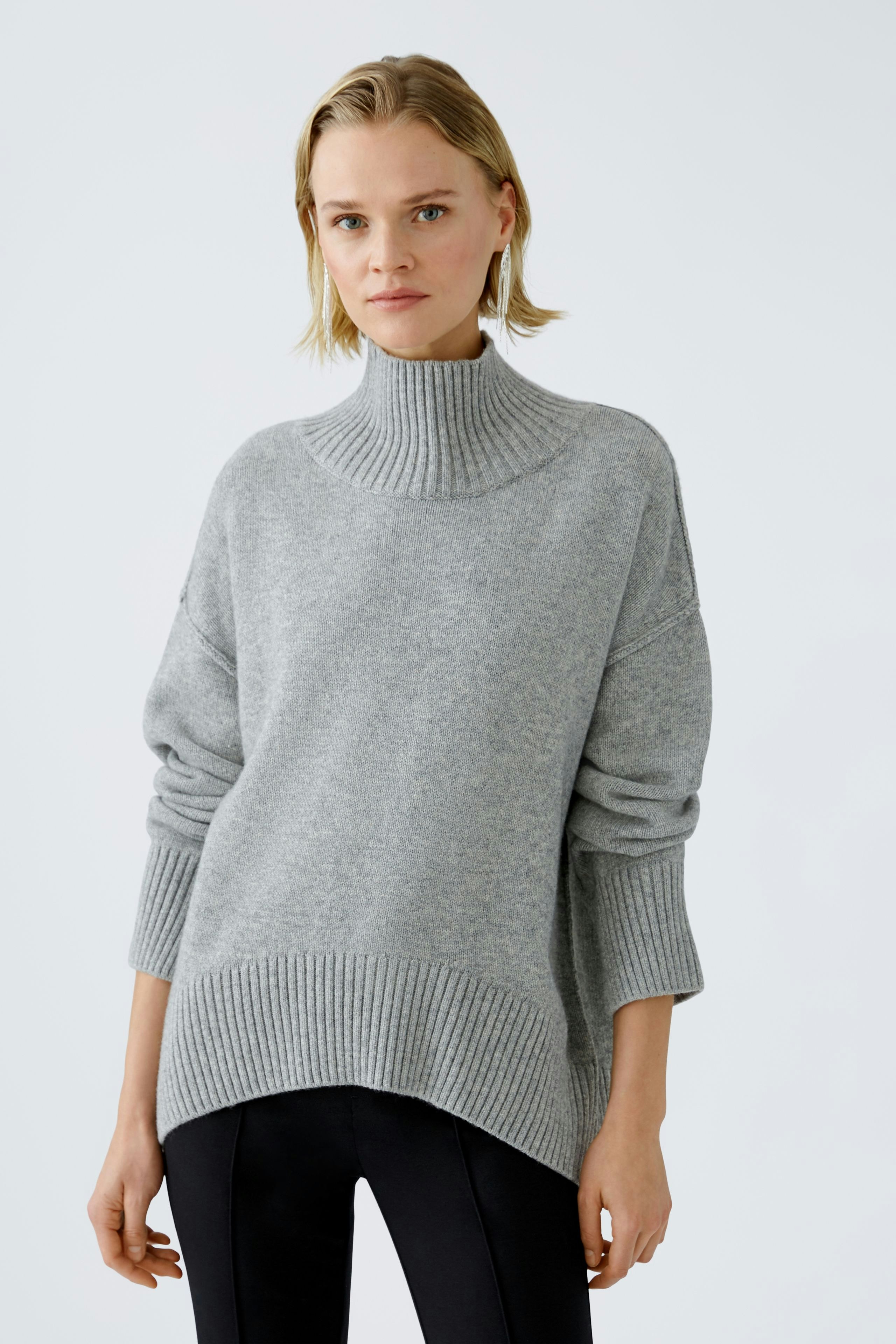 Modern women's pullover: A woman in a cozy gray pullover with a high neck and relaxed fit.
