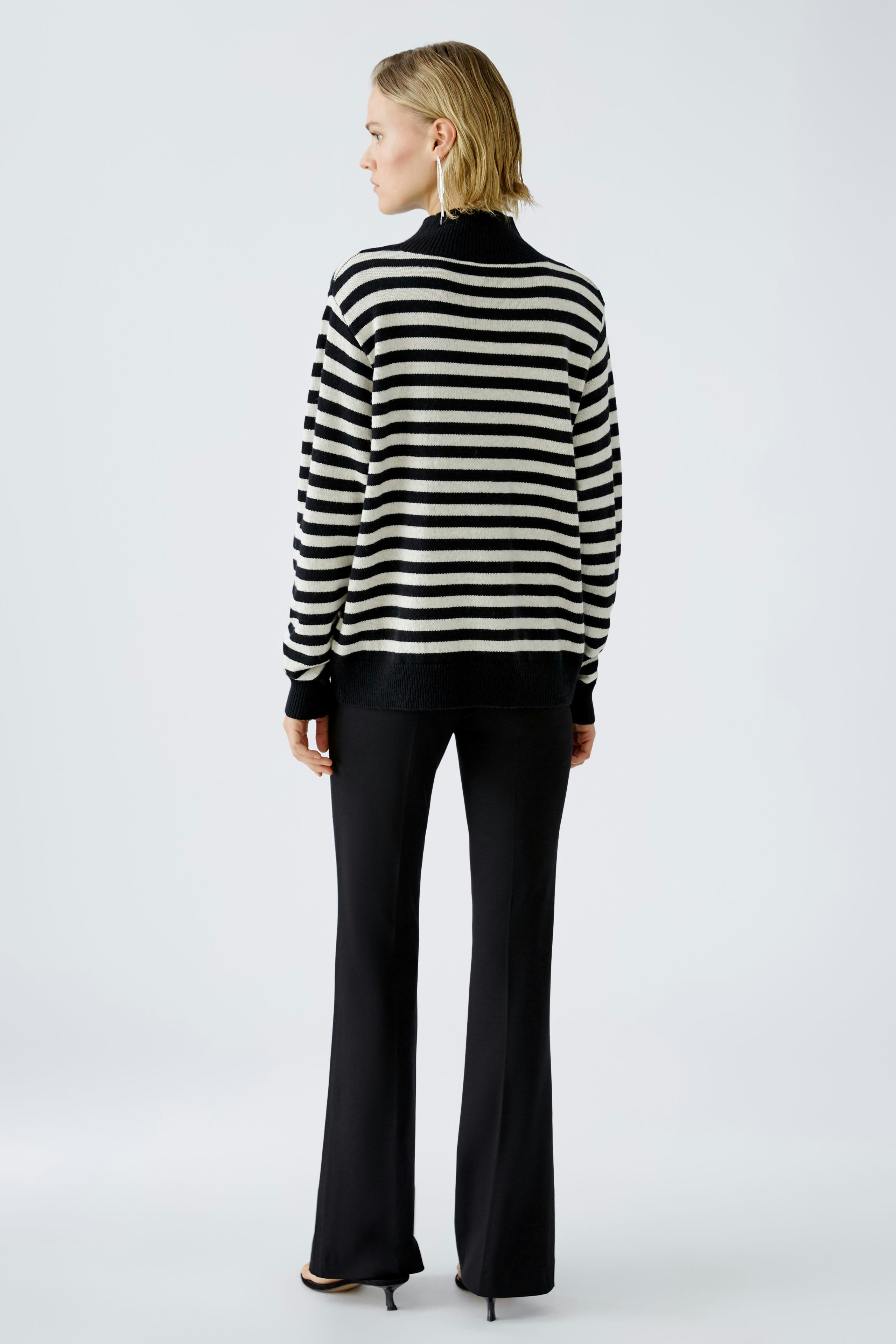 Damen-Pullover: Frau in gestreiftem Pullover mit hohem Kragen und eleganten Hosen von hinten.