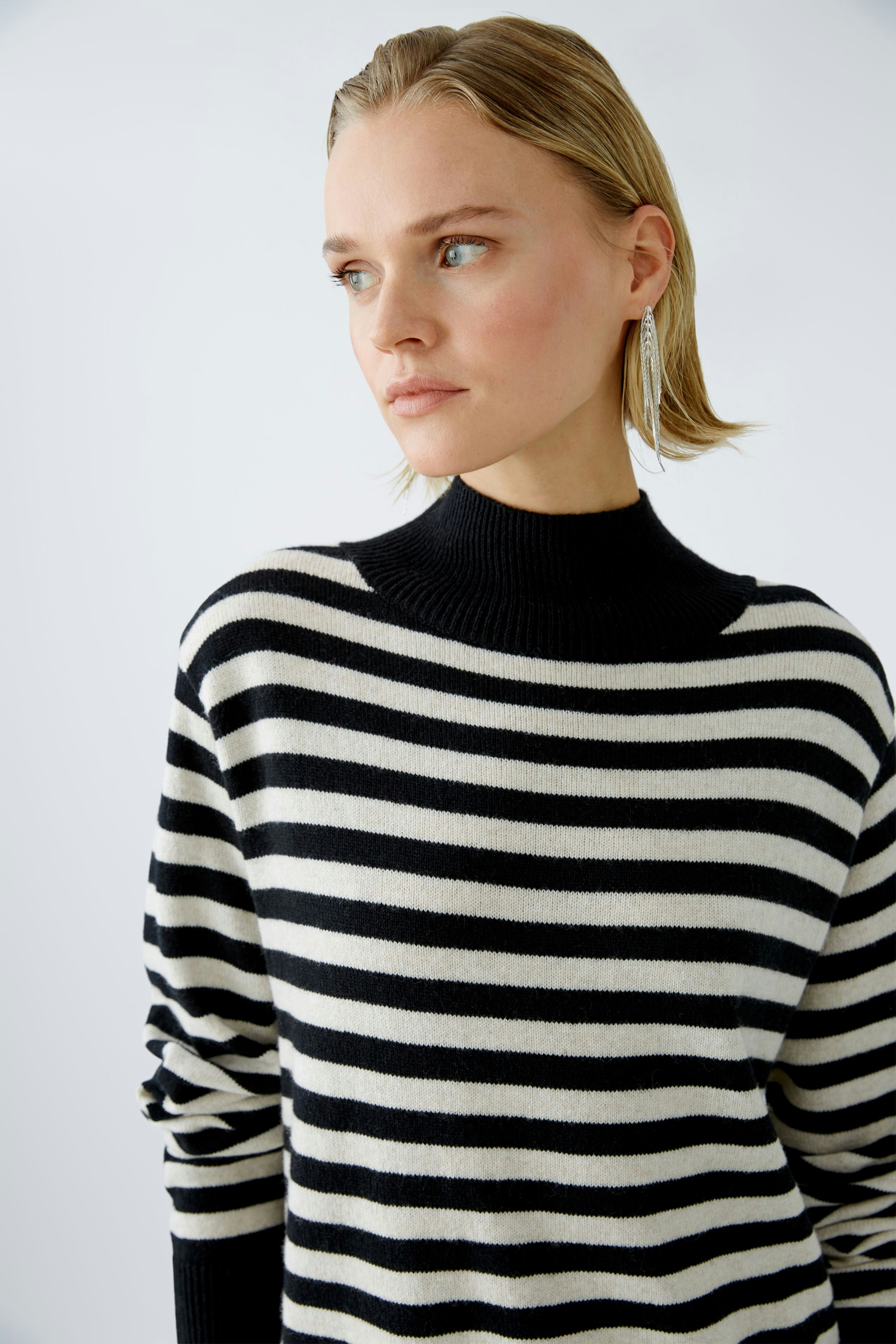 Damen-Pullover: Frau in gestreiftem Pullover mit hohem Kragen, elegant und lässig zugleich.
