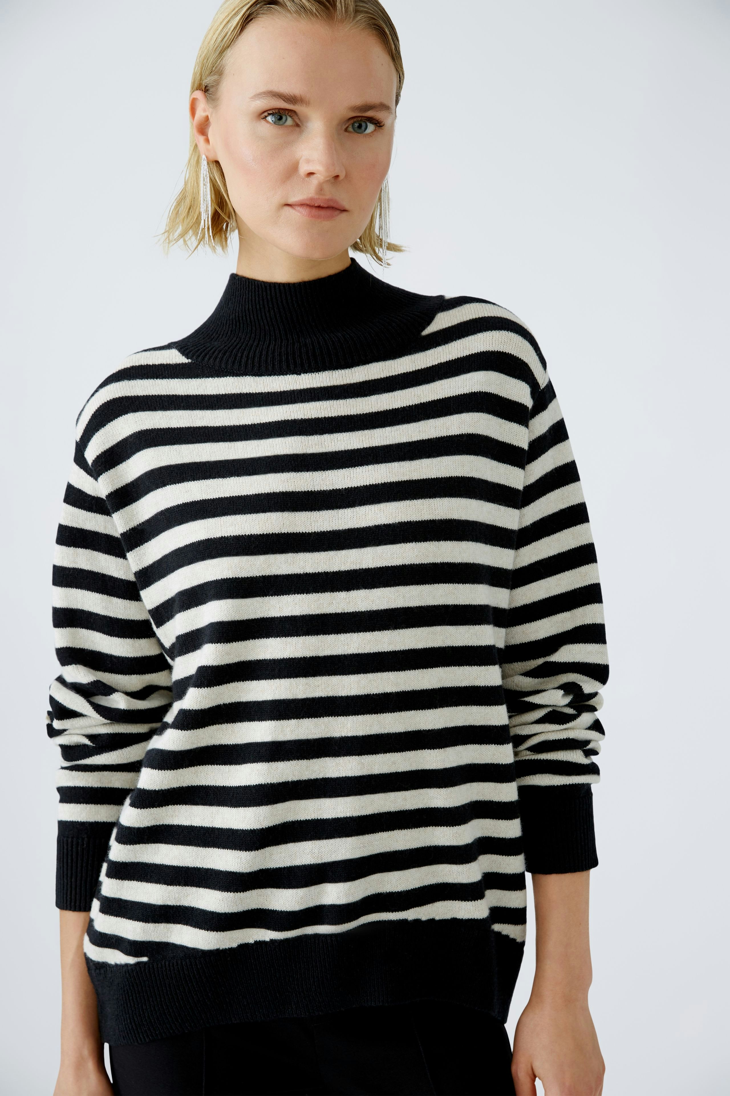 Damen-Pullover: Frau in gestreiftem Pullover mit hohem Kragen, lässig und modern.