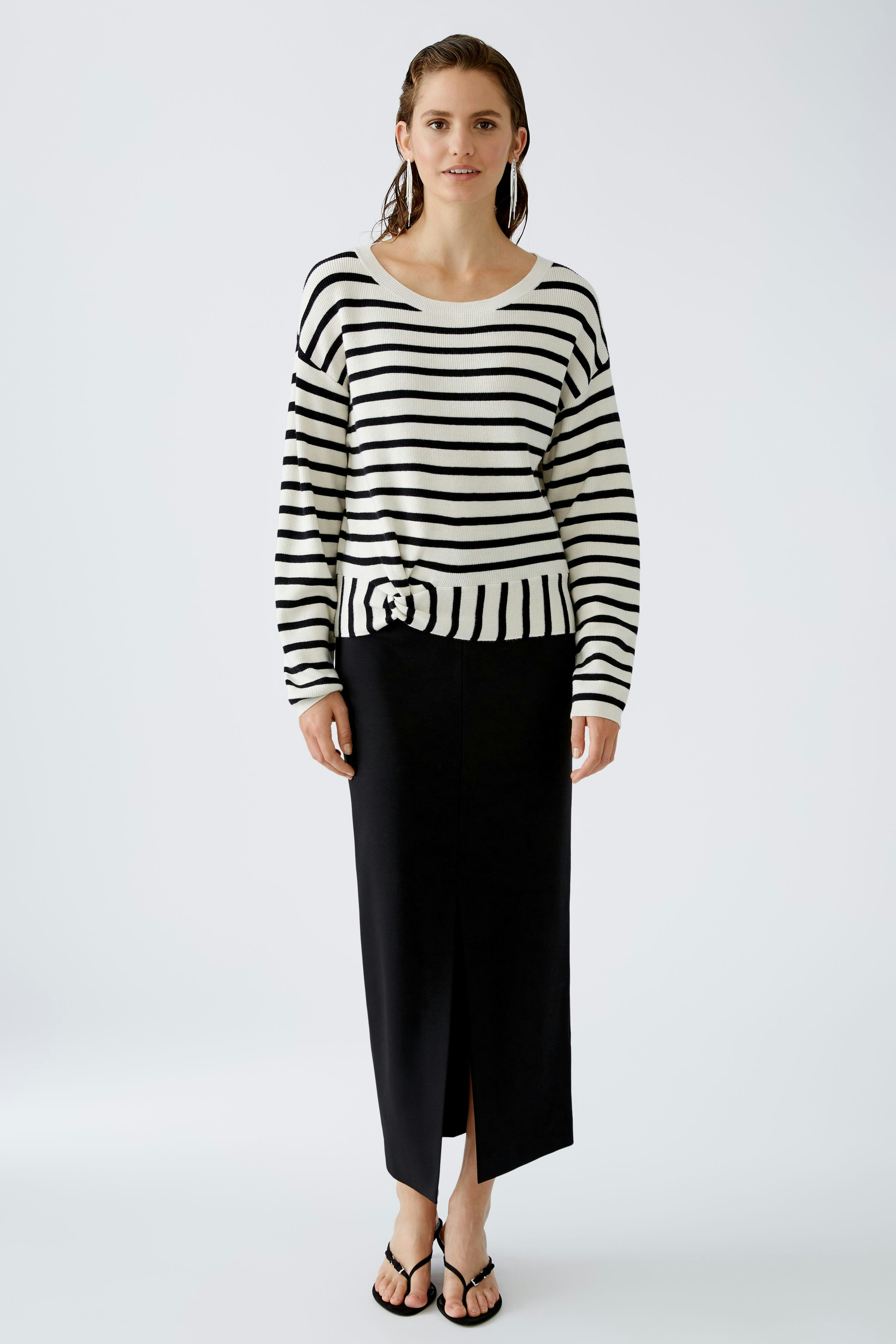 Modern pullover: Woman in a striped pullover paired with a sleek black skirt, exuding effortless style.