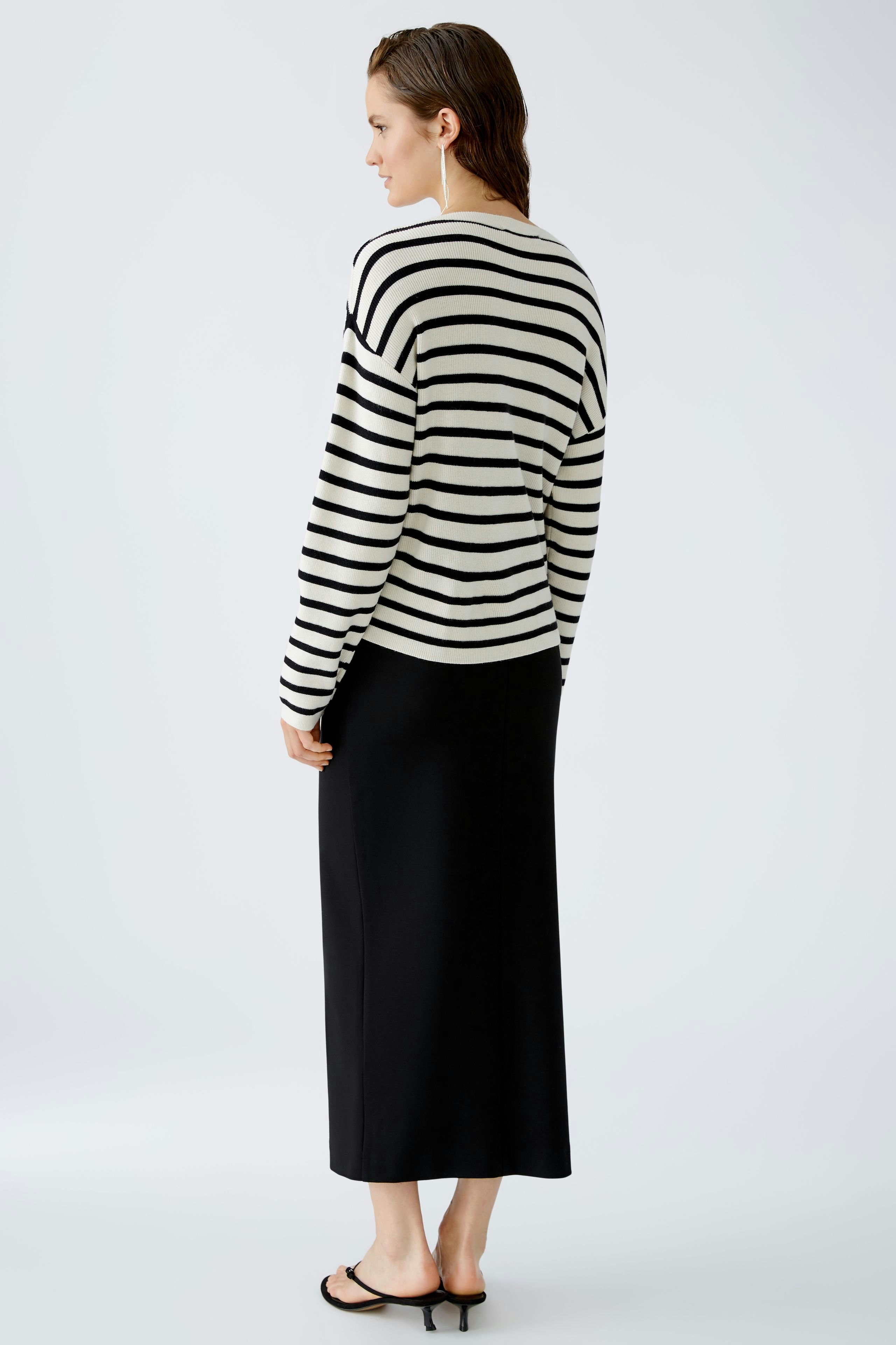 Stylish women's pullover: A woman in a striped pullover and black skirt stands confidently.