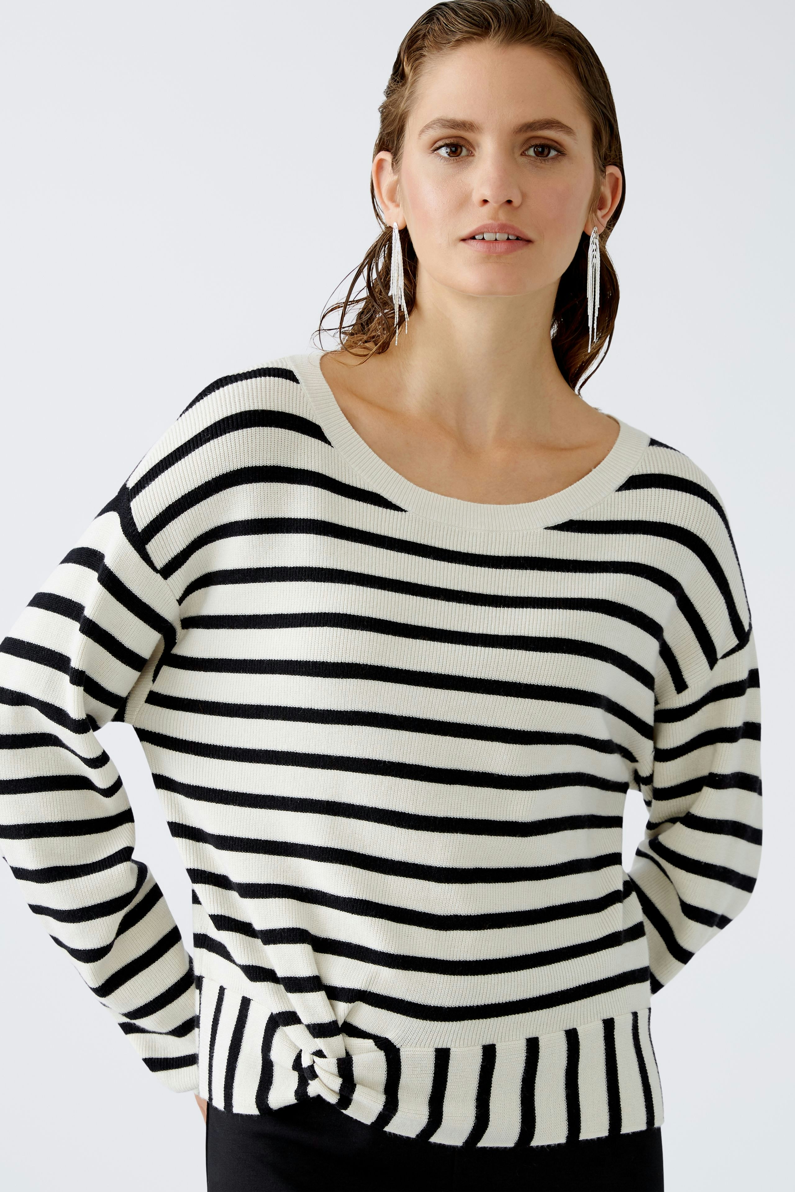 Modern women's pullover: A woman in a striped pullover with a relaxed fit poses confidently.