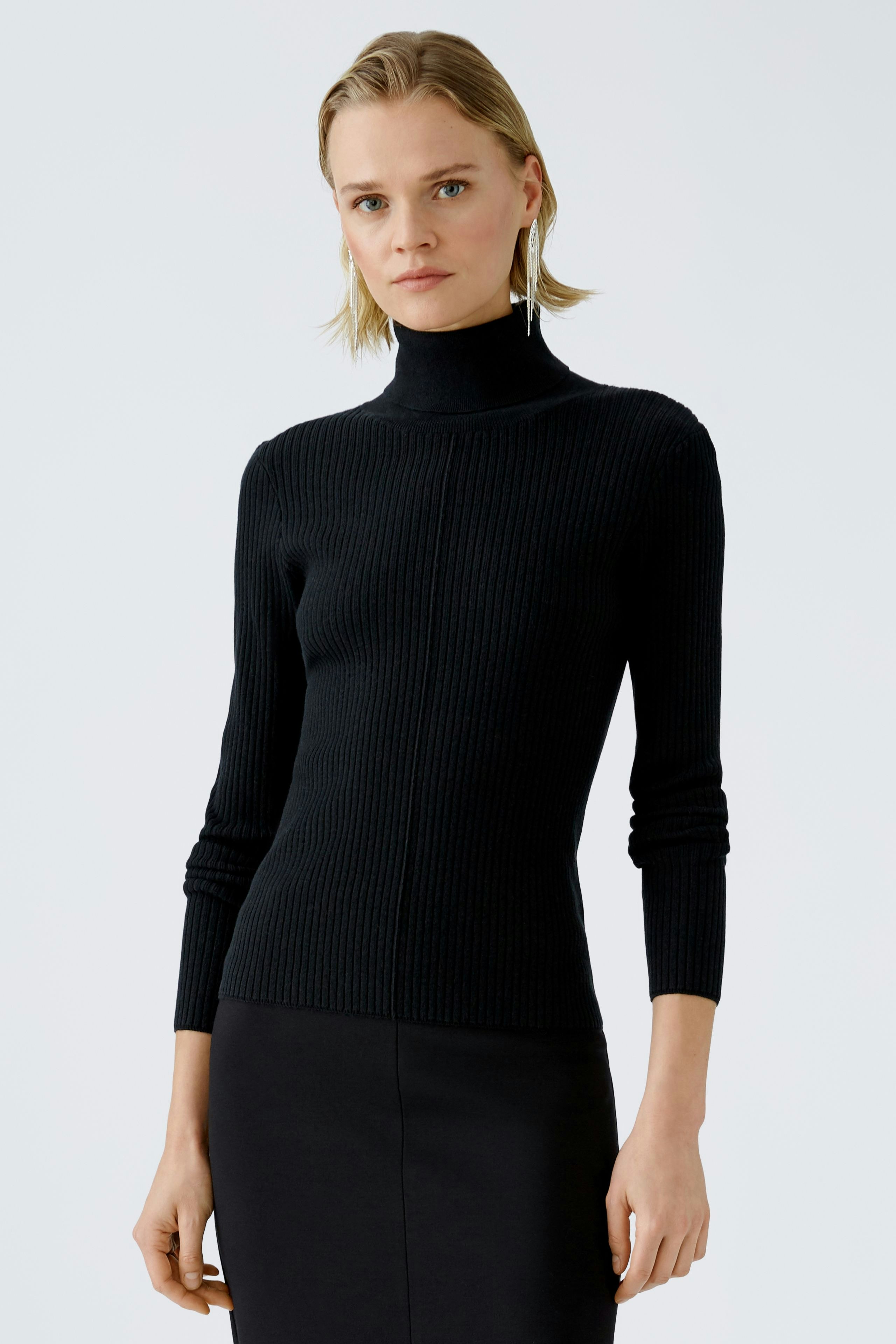 Modern women's pullover: A woman in a black ribbed pullover with a high neck, exuding elegance.