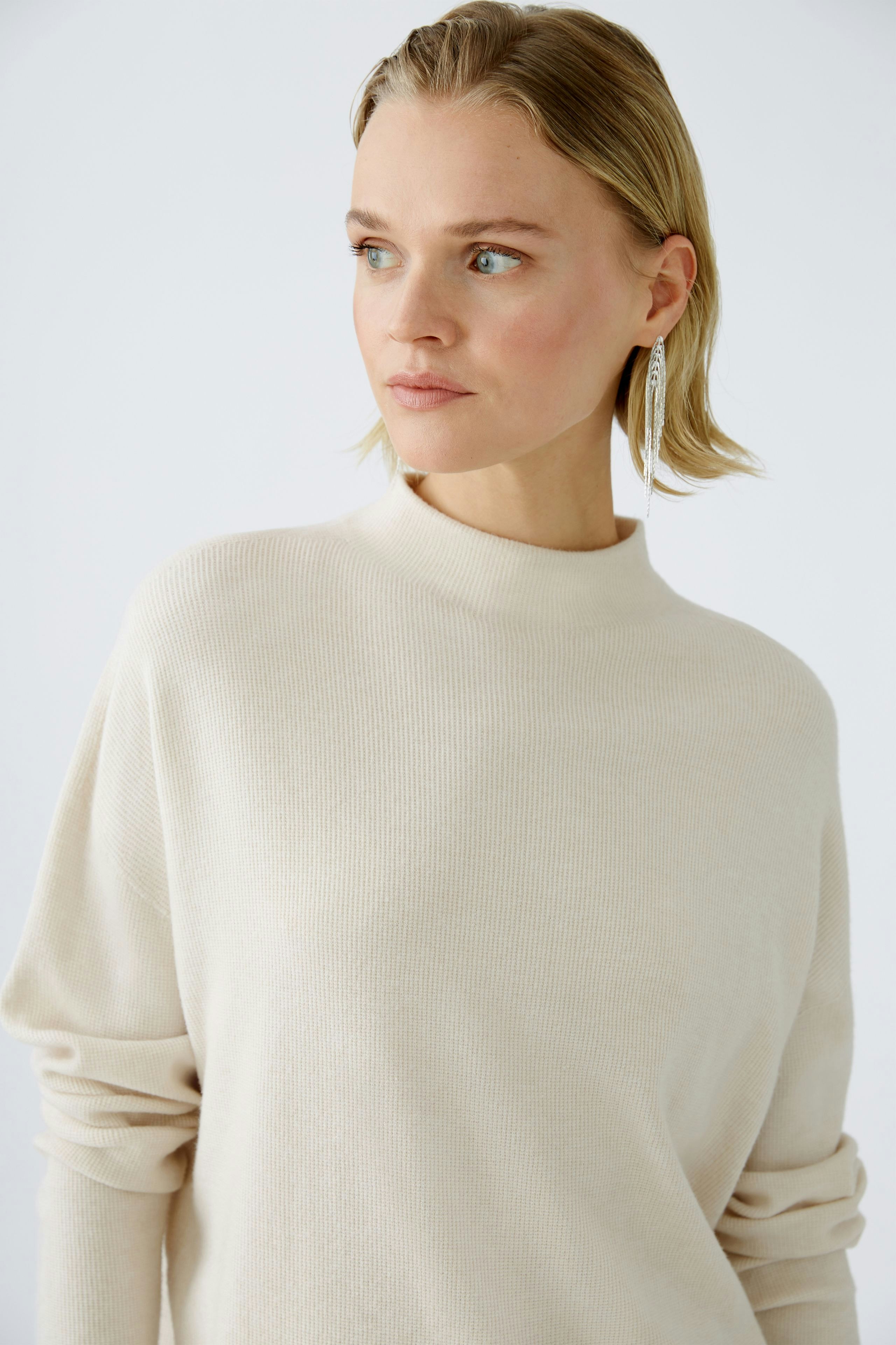 Modern women's pullover: A woman in a cream pullover with a high neckline, exuding elegance.