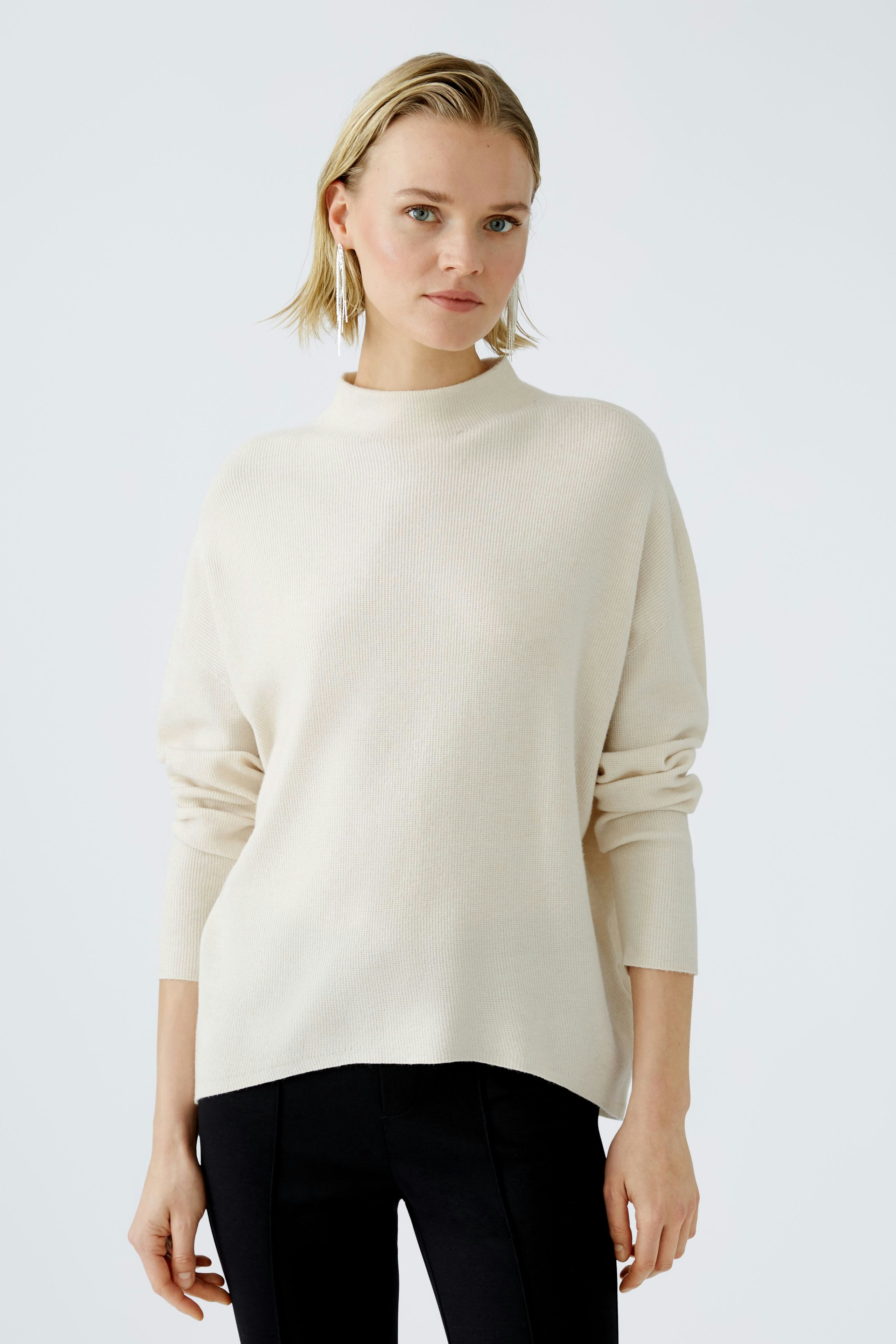 Modern women's pullover: Young woman in a cream pullover with a relaxed fit, exuding effortless style.