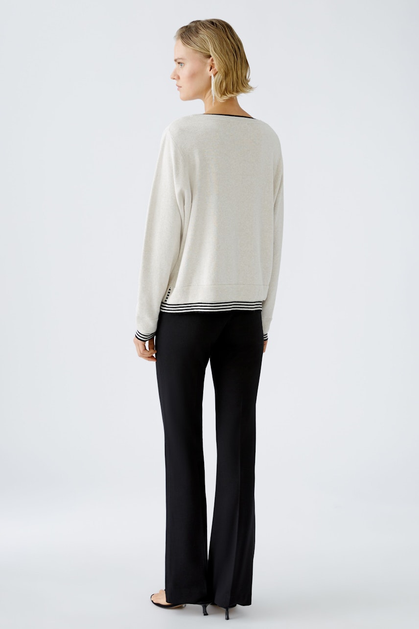 Stylish women's pullover: A woman in a light pullover with striped hem, showcasing a relaxed fit.