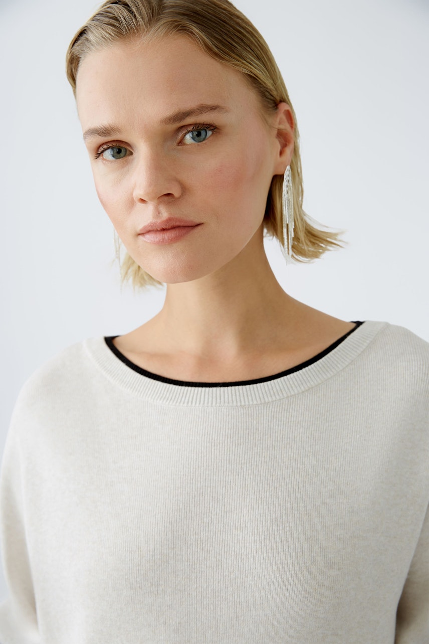 Modern women's pullover: A woman in a light beige pullover with a relaxed fit and minimalistic style.