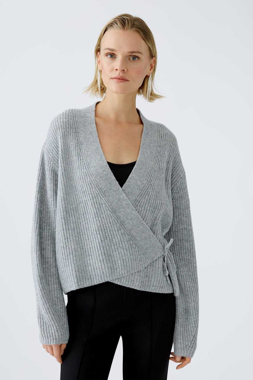 Stylish women's cardigan: A woman in a light gray wrap cardigan with a relaxed fit.