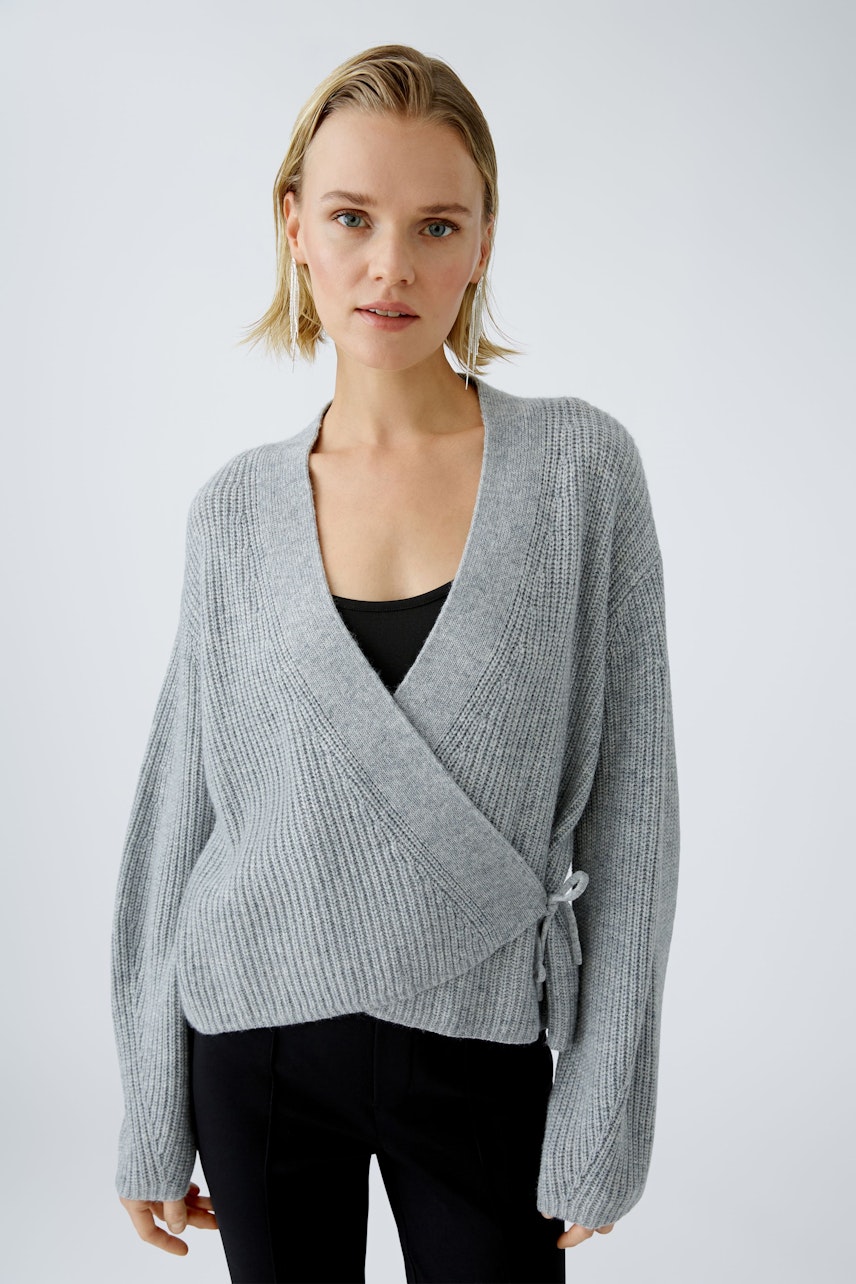 Stylish women's cardigan: A woman in a gray wrap cardigan with a relaxed fit and soft texture.