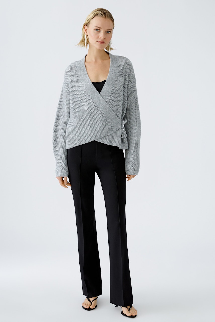 Stylish women's cardigan: A woman in a gray wrap cardigan paired with sleek black pants.