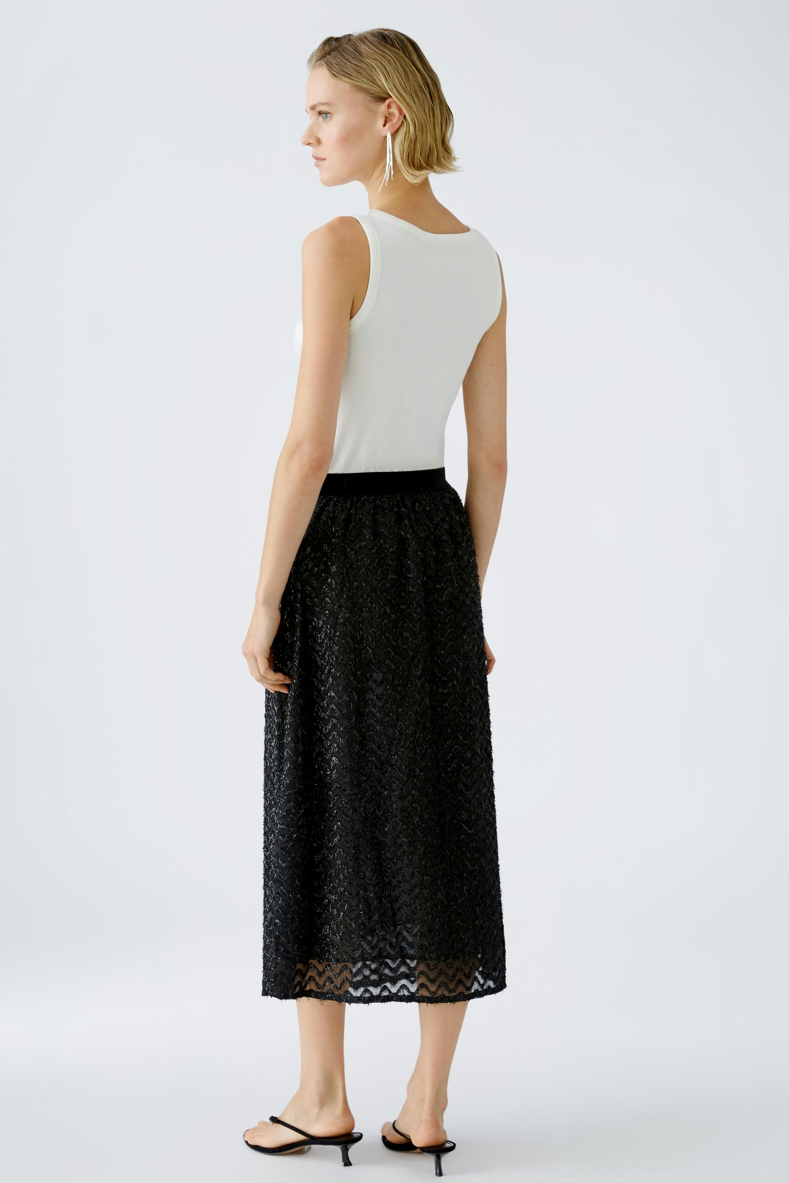 Elegant black skirt: Woman in a stylish black skirt with a textured design, showcasing modern fashion.