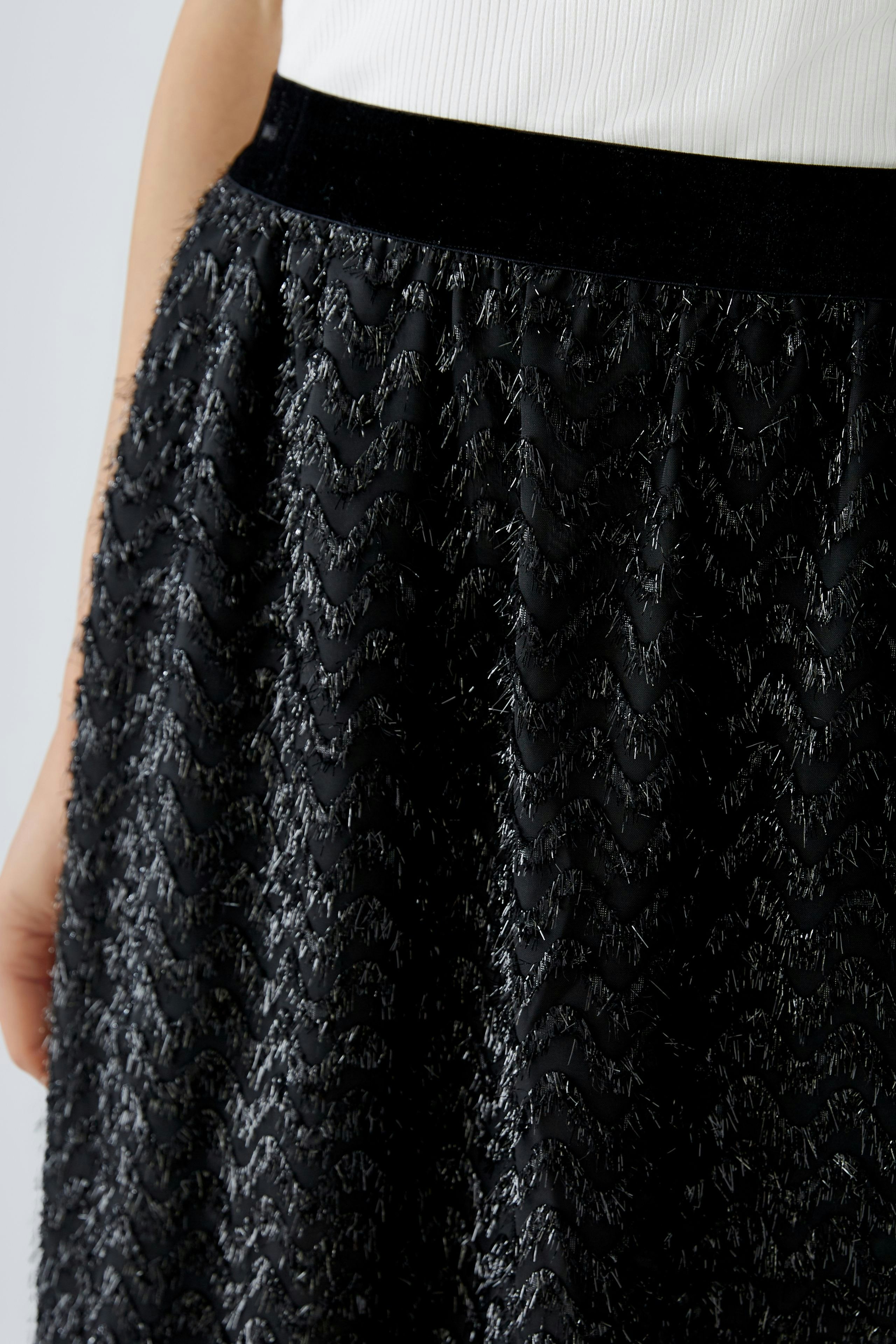 Elegant black skirt: Woman in a textured skirt with a wavy pattern, showcasing a chic and modern style.