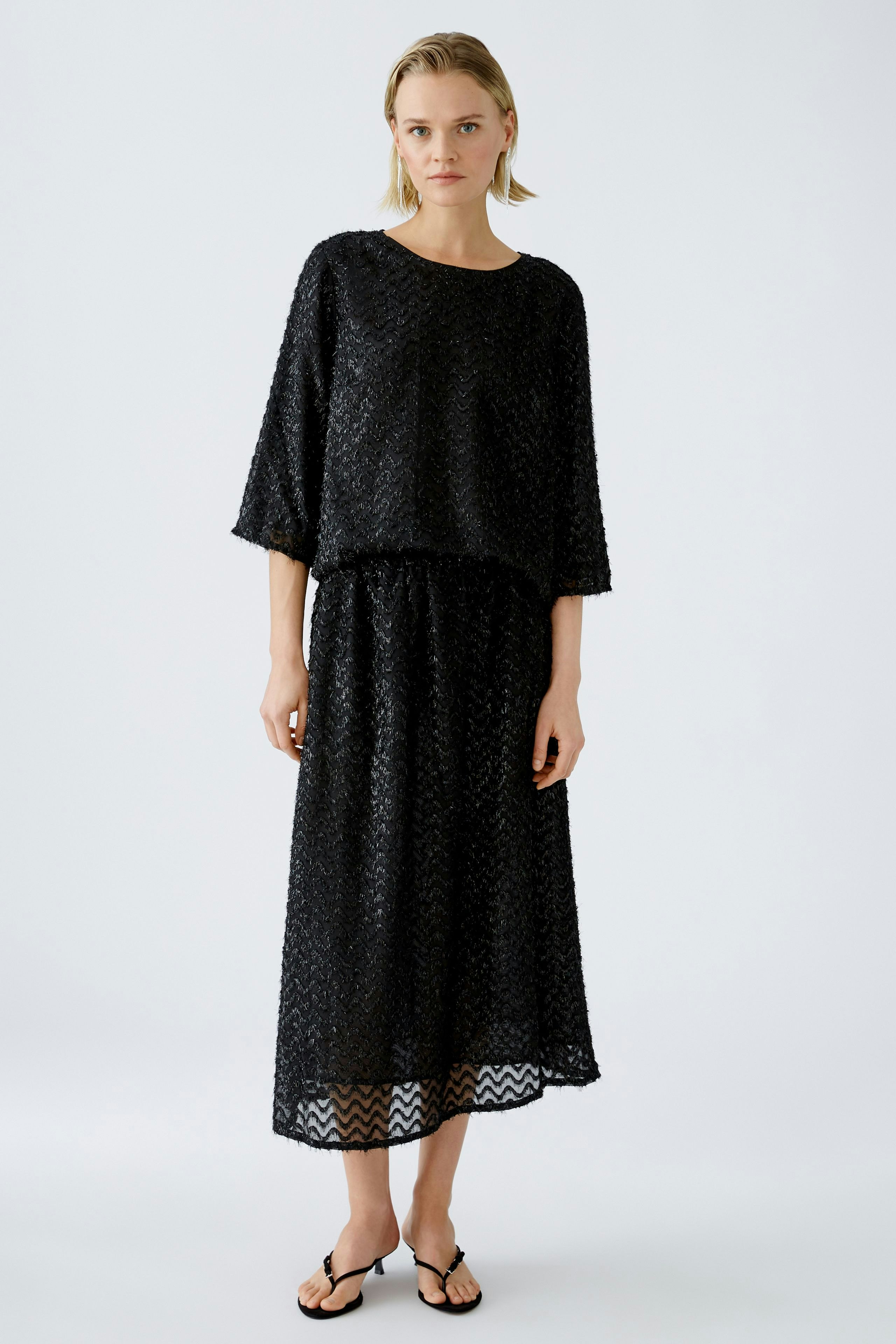 Elegant black pullover and skirt set: Young woman in a stylish, textured outfit exudes sophistication.