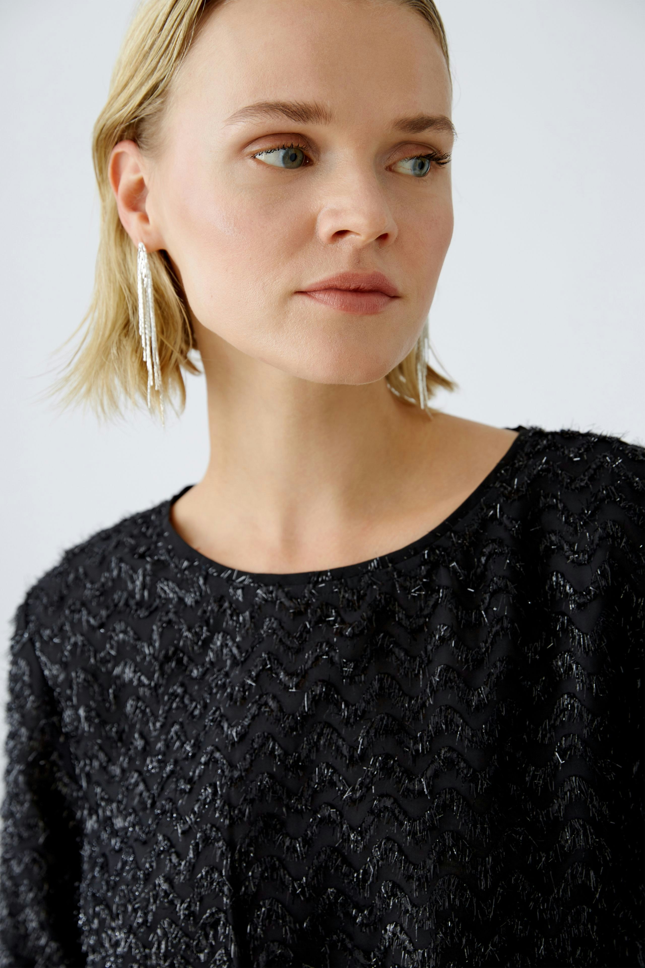 Elegant women's pullover: A woman in a textured black pullover with a chic design, exuding sophistication.