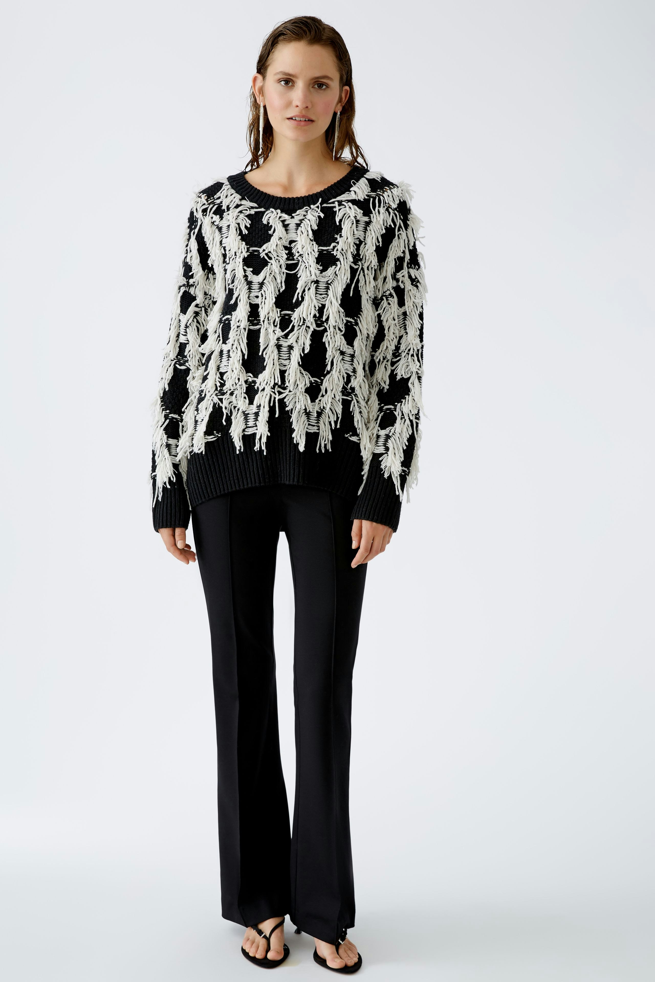 Chic flared trousers: A woman in stylish black flared trousers paired with a trendy pullover.