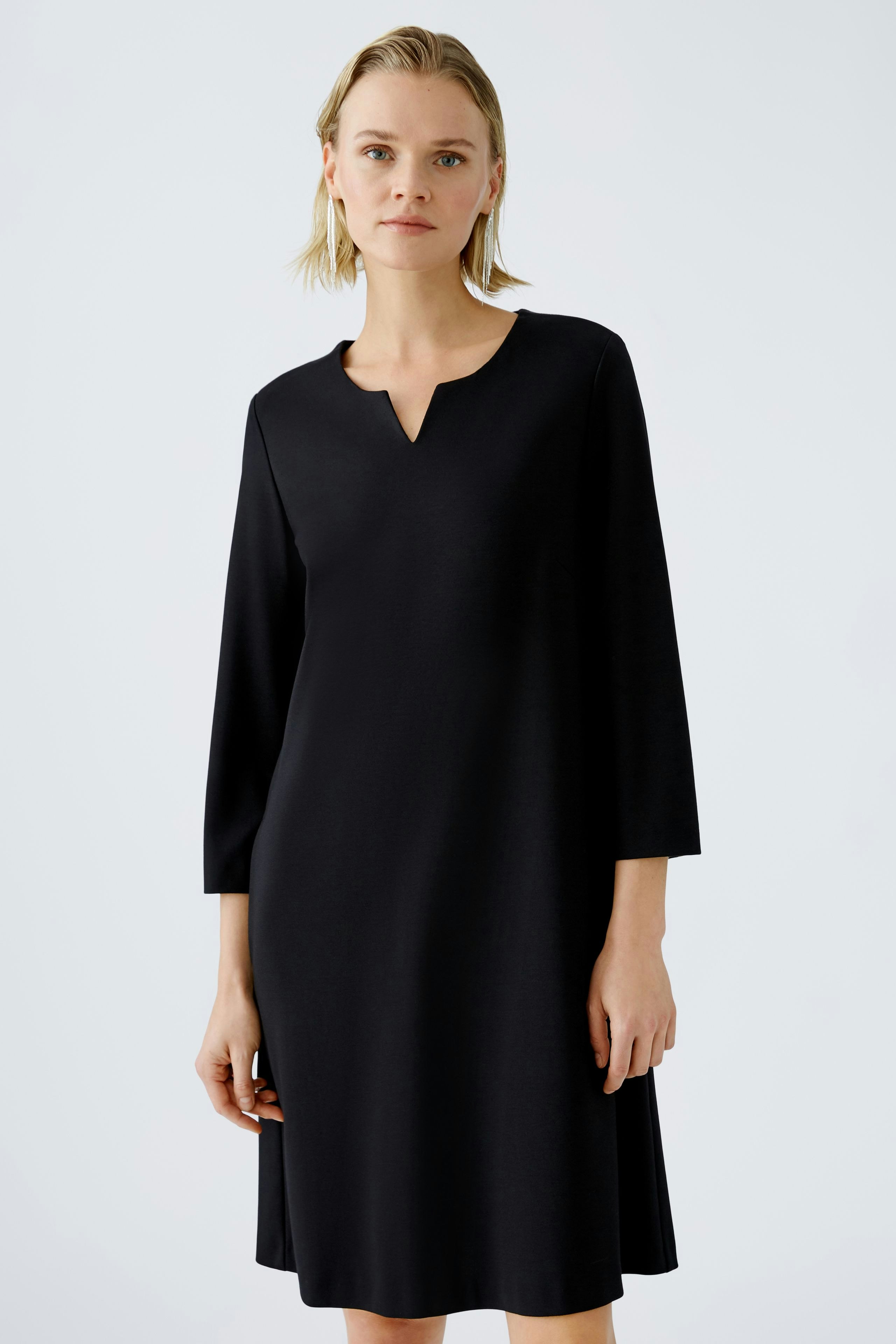 Elegant A-line dress: A woman in a black A-line dress with three-quarter sleeves poses confidently.