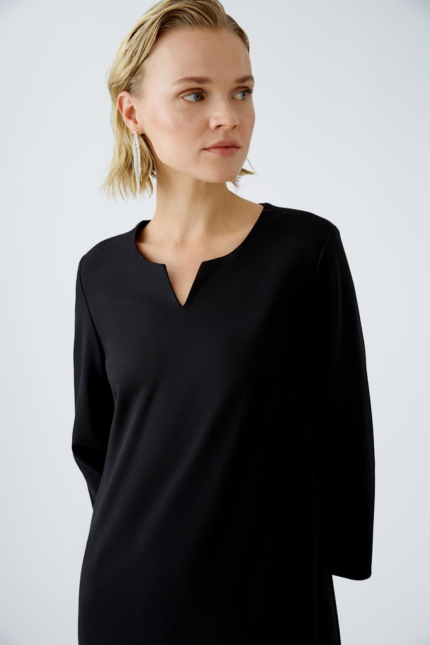 Elegant A-line dress: A woman in a sleek black dress with a subtle neckline, exuding sophistication.