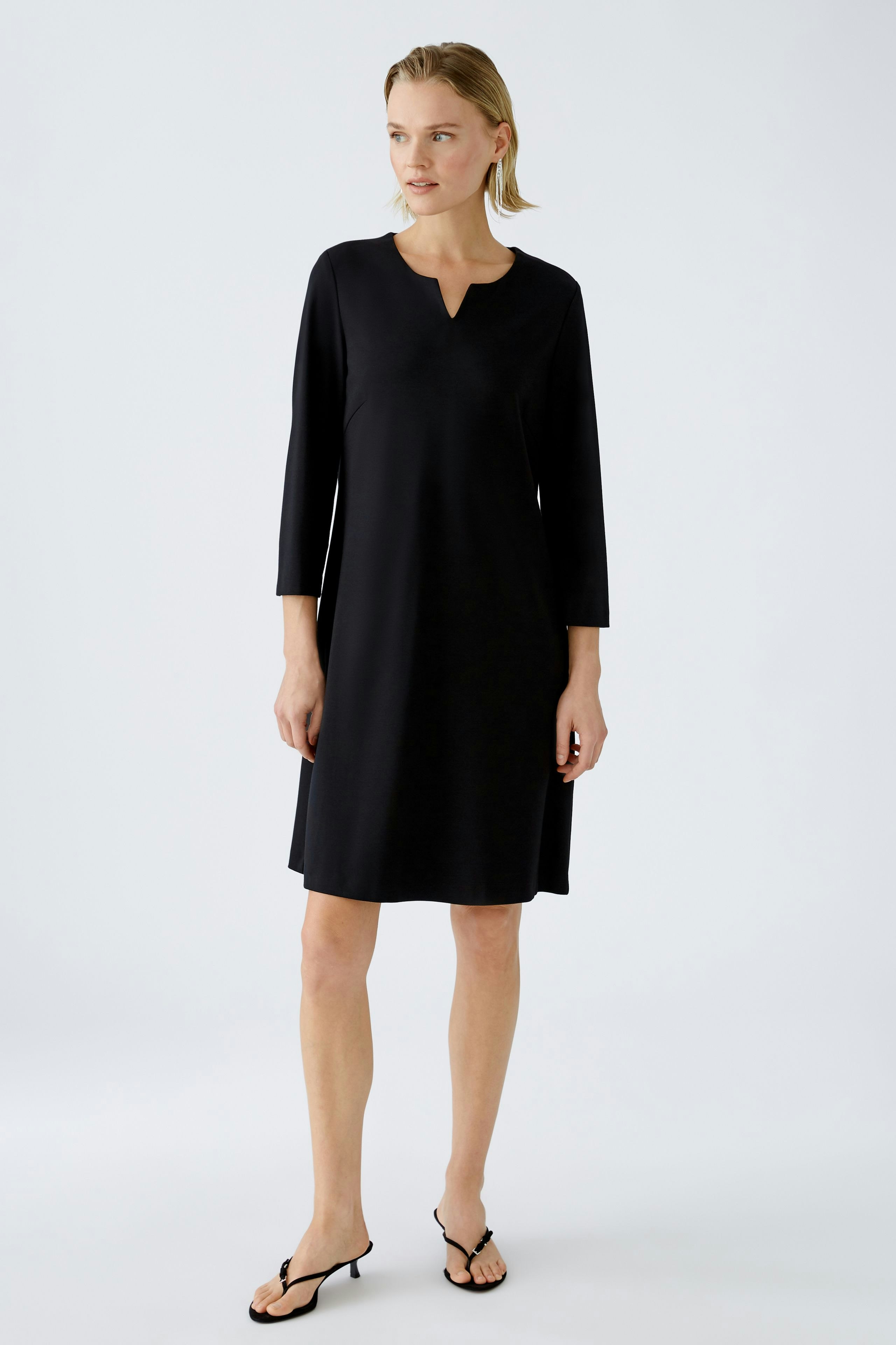Elegant A-line dress: A woman in a black A-line dress with three-quarter sleeves stands confidently.