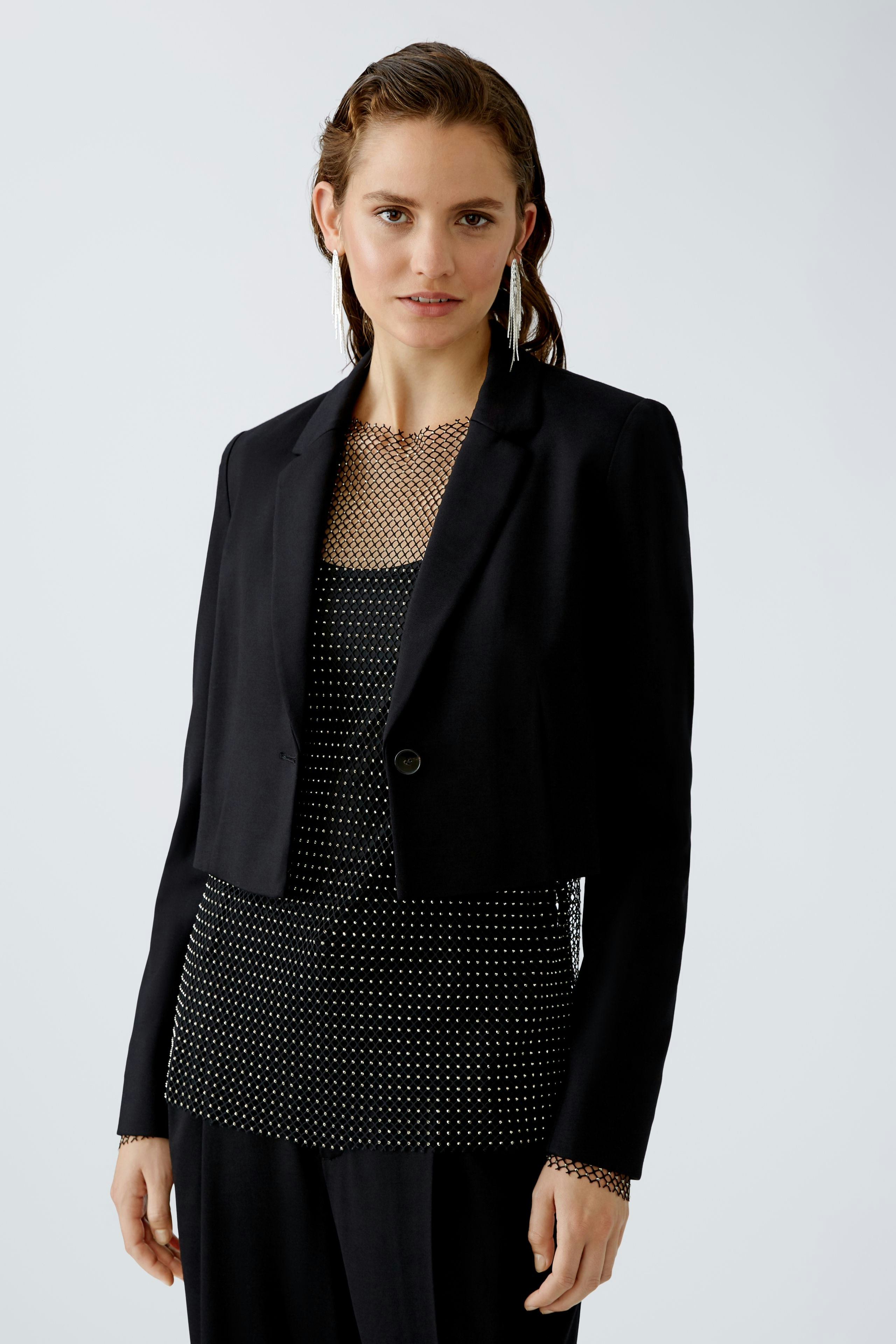Eleganter Damen-Blazer: Frau in schwarzem Blazer über gepunktetem Top, stilvoll und modern.