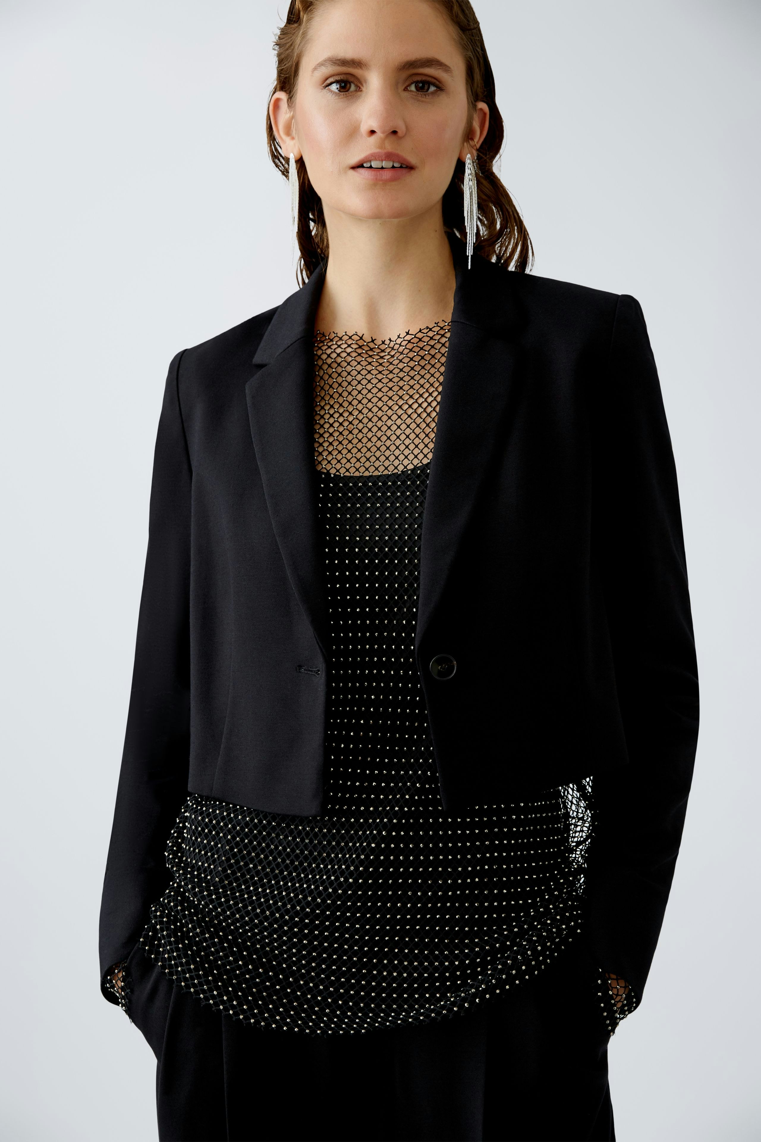 Eleganter Damen-Blazer: Frau trägt einen schwarzen Blazer über einem gepunkteten Top.