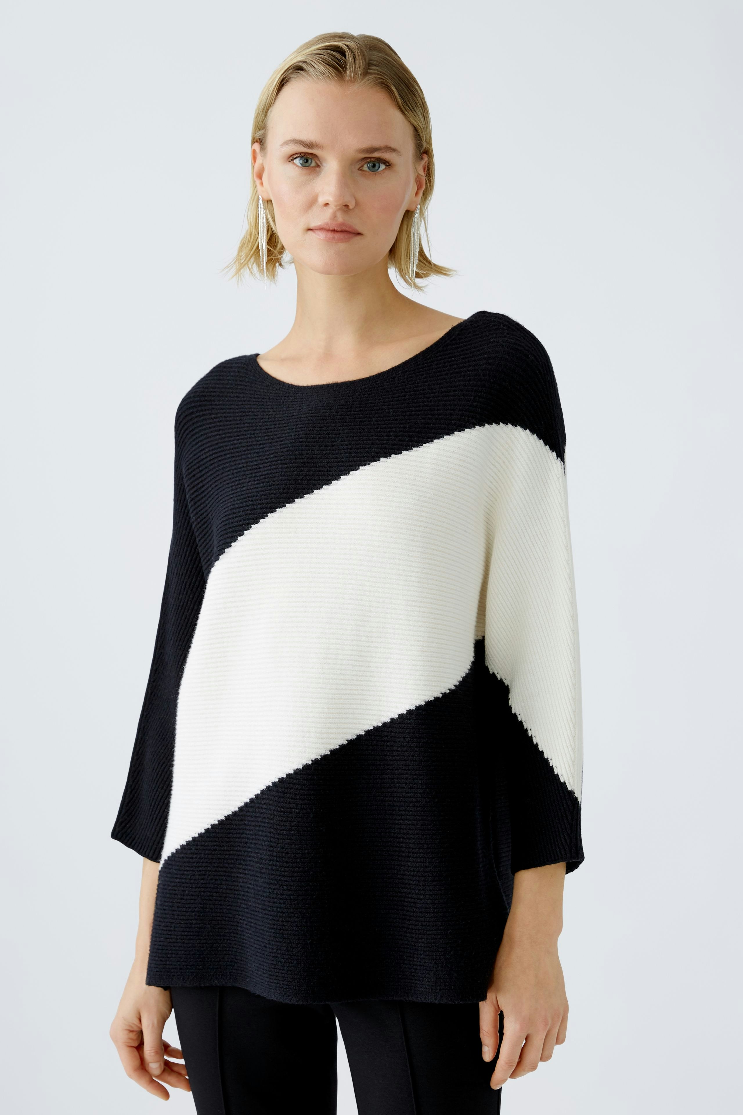 Modern women's pullover: A woman in a stylish black and white striped pullover stands confidently.