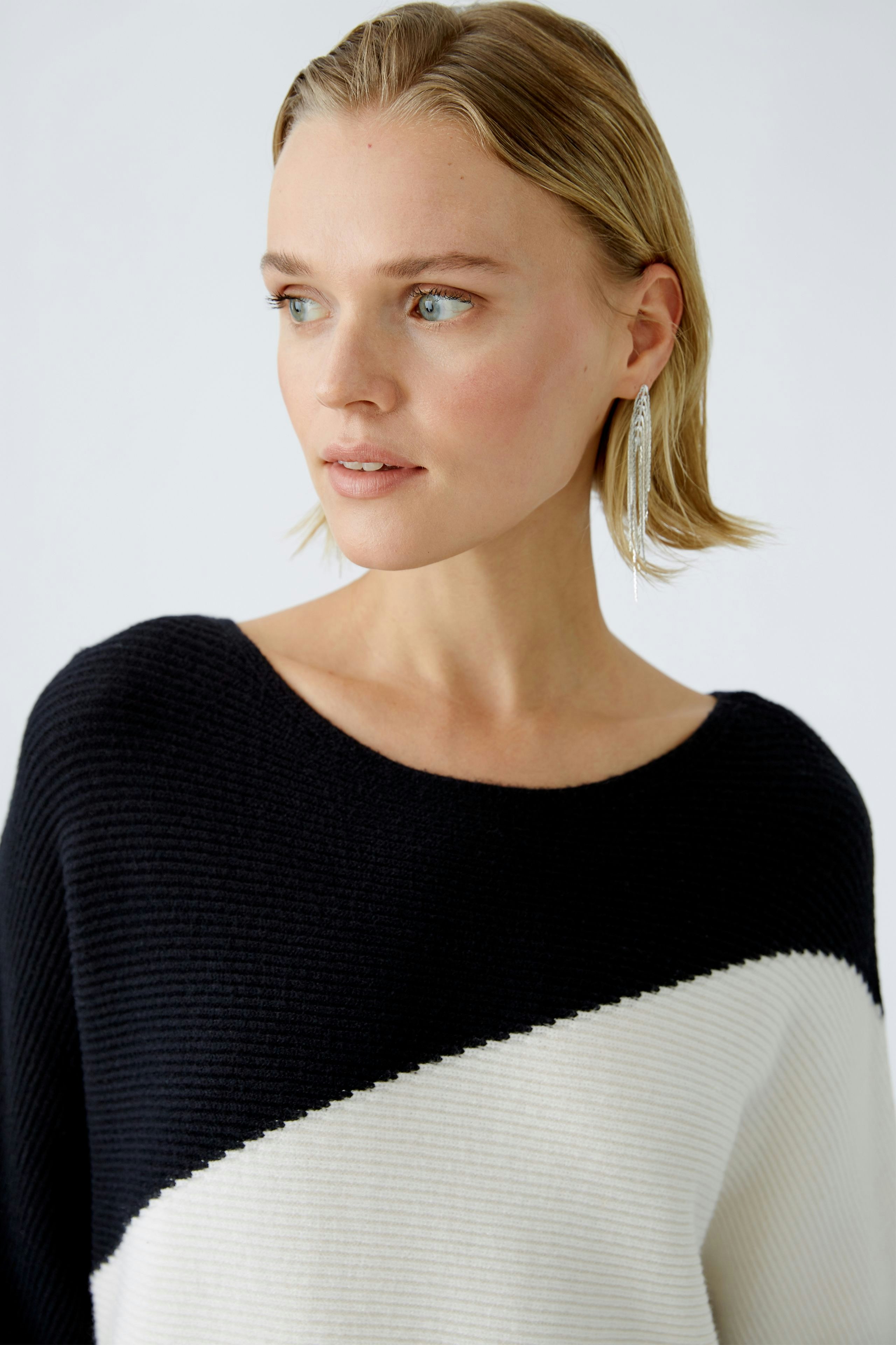 Modern pullover: Woman in a stylish black and white pullover, showcasing a chic and casual look.