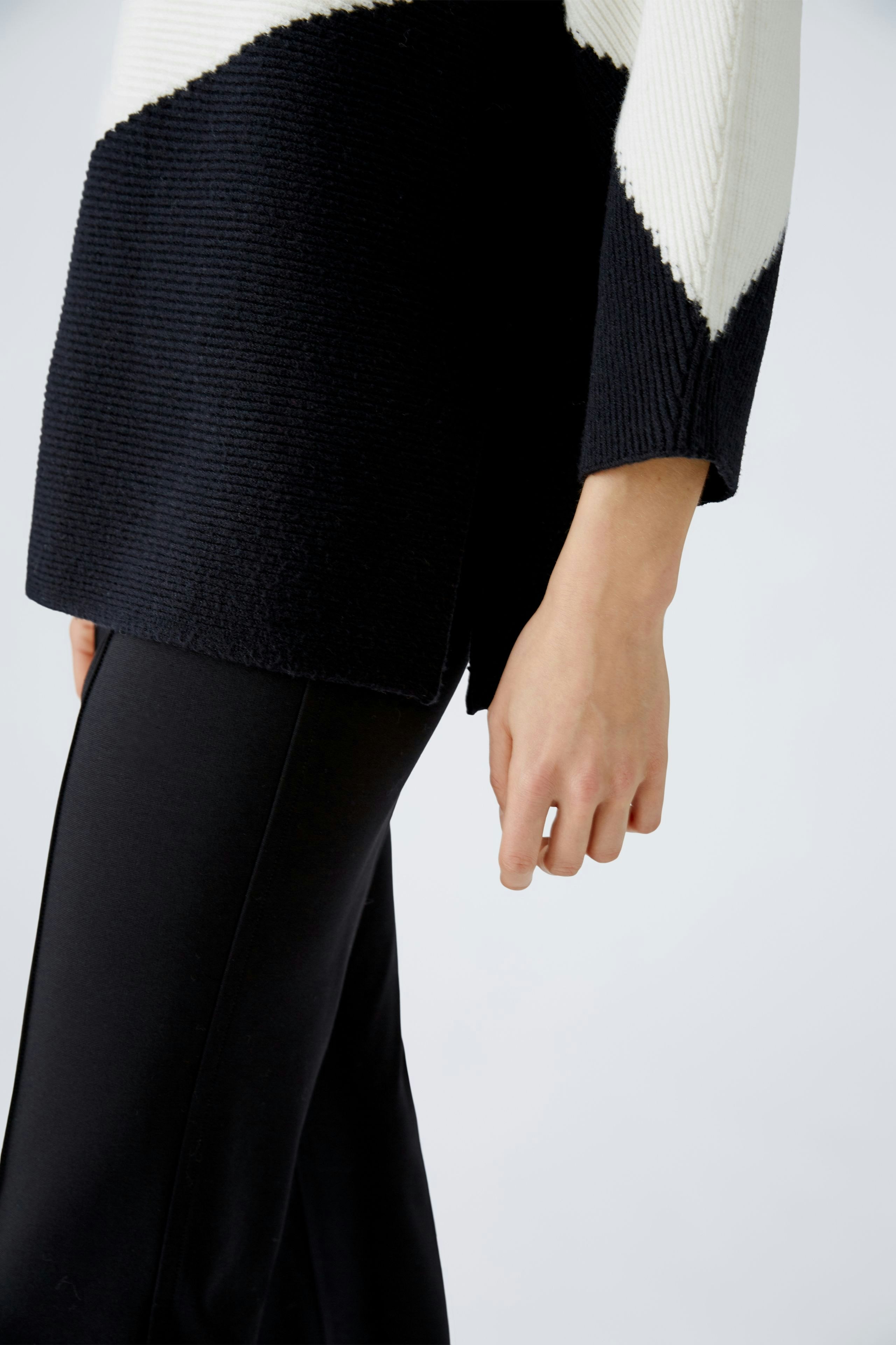 Stylish women's pullover: A woman in a black and white textured pullover, showcasing modern elegance.