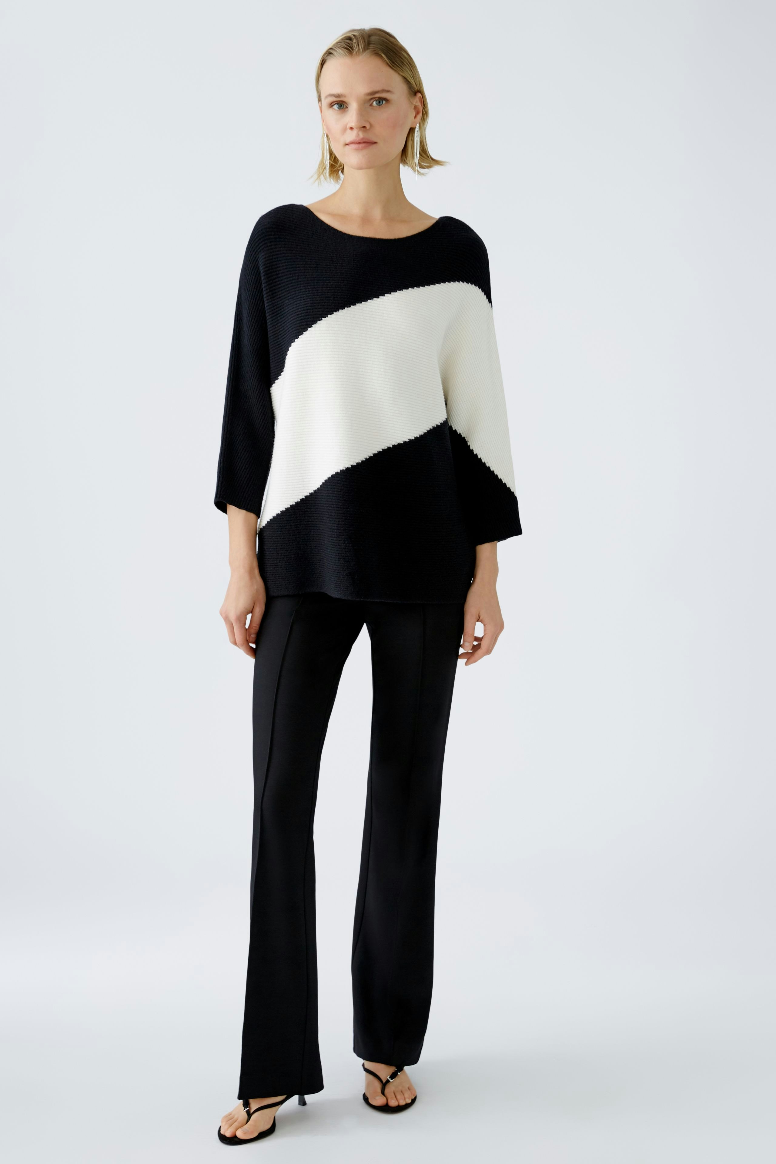 Modern women's pullover: A woman in a black and white striped pullover stands confidently.