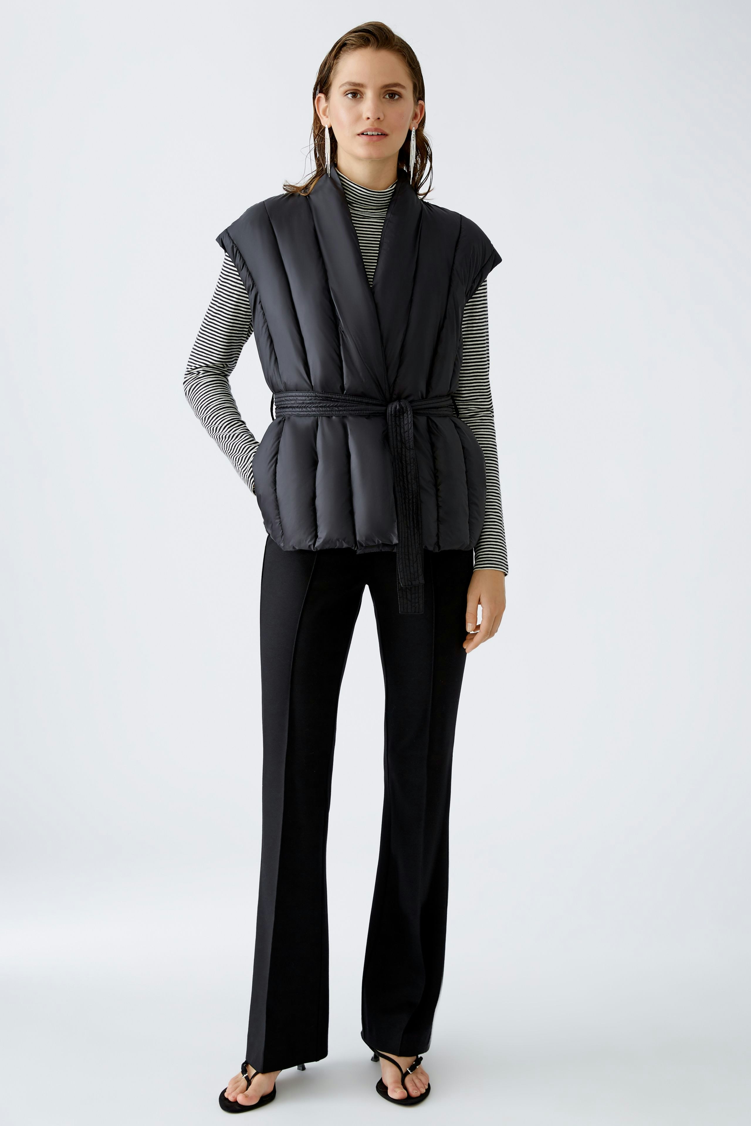 Stylish women's vest: A woman in a black knitted vest over a striped top, exuding modern elegance.