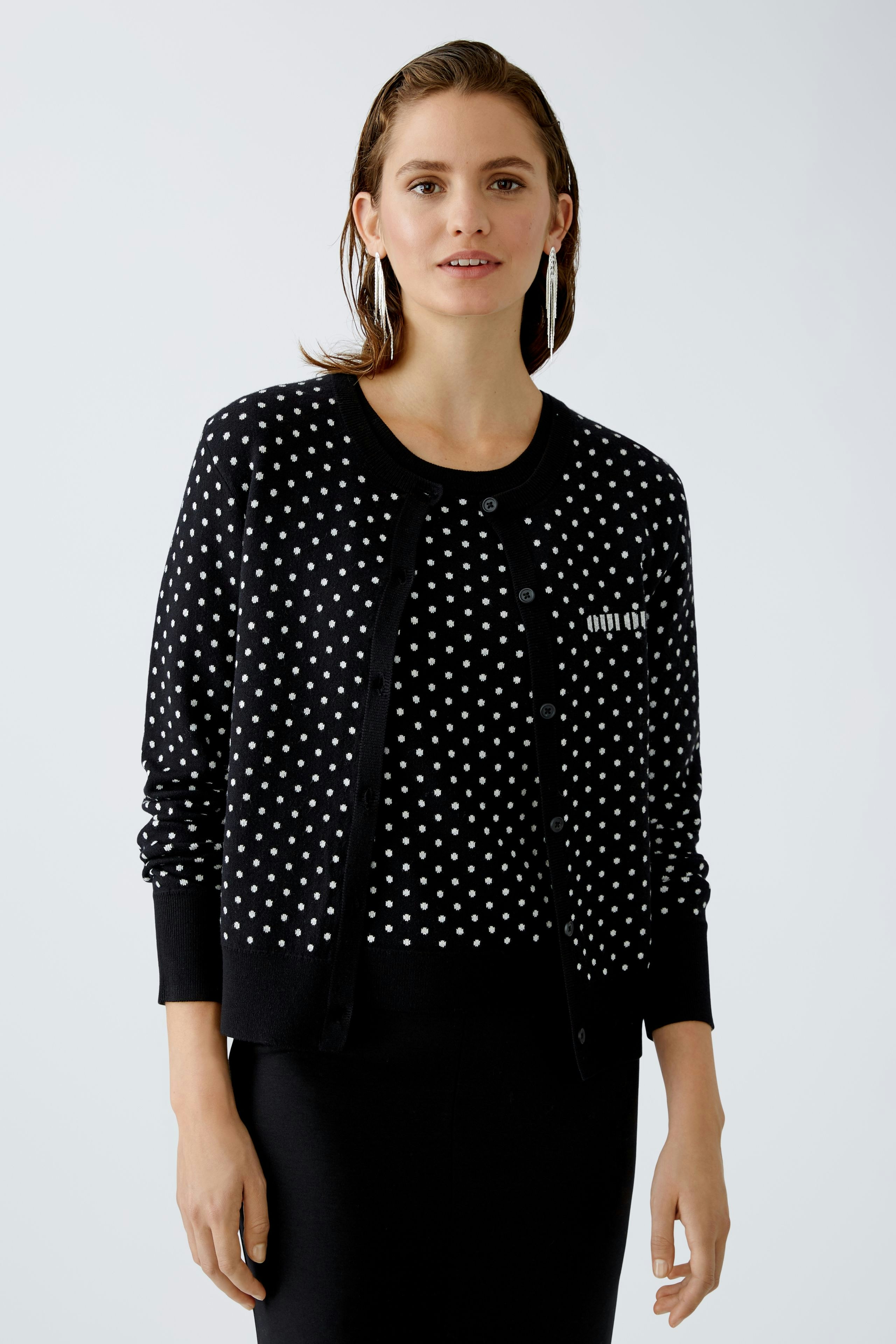 Chic women's cardigan: Young woman in a black polka dot cardigan, exuding elegance and style.