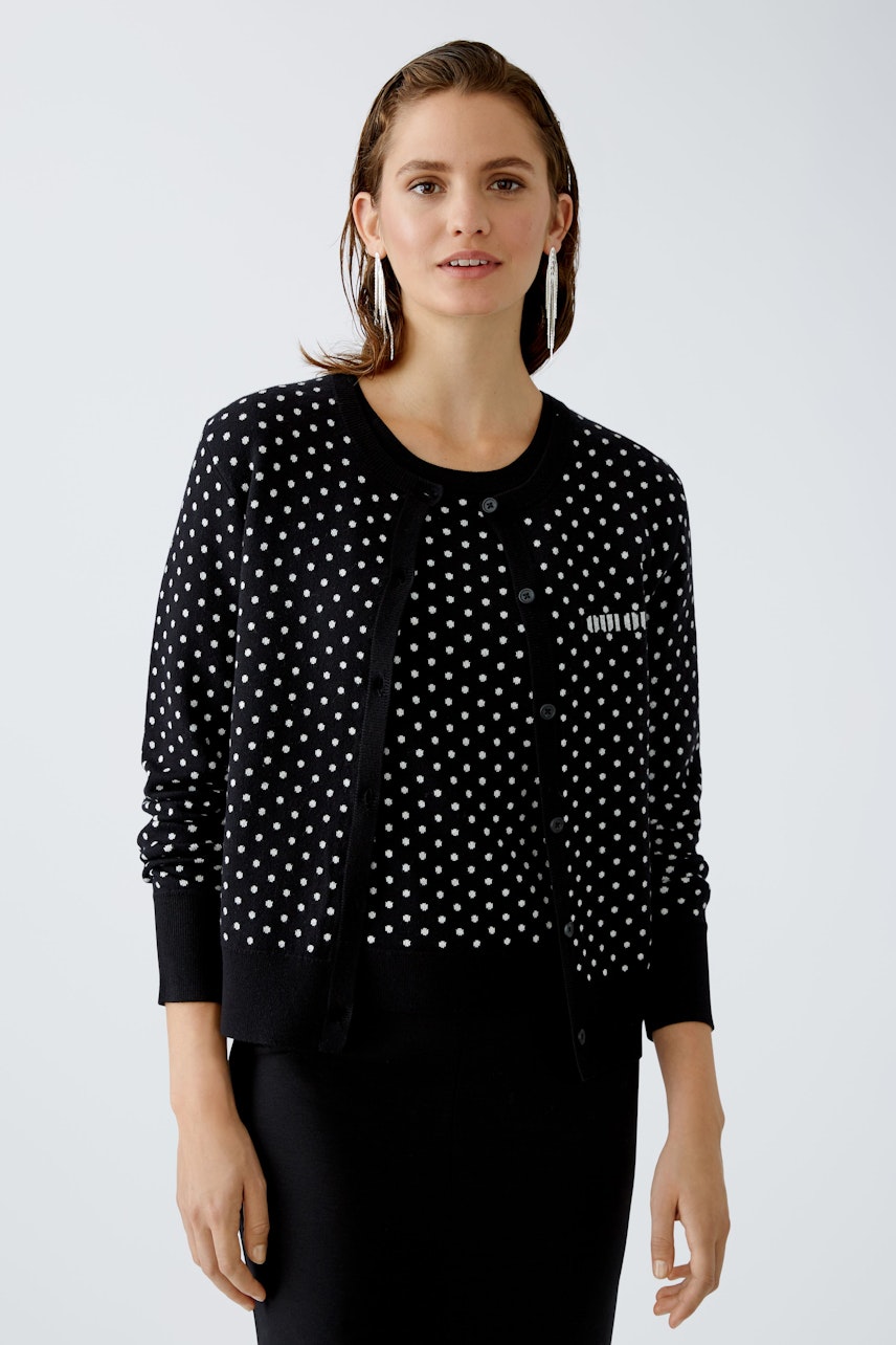 Chic women's cardigan: Young woman in a black polka dot cardigan, exuding elegance and style.