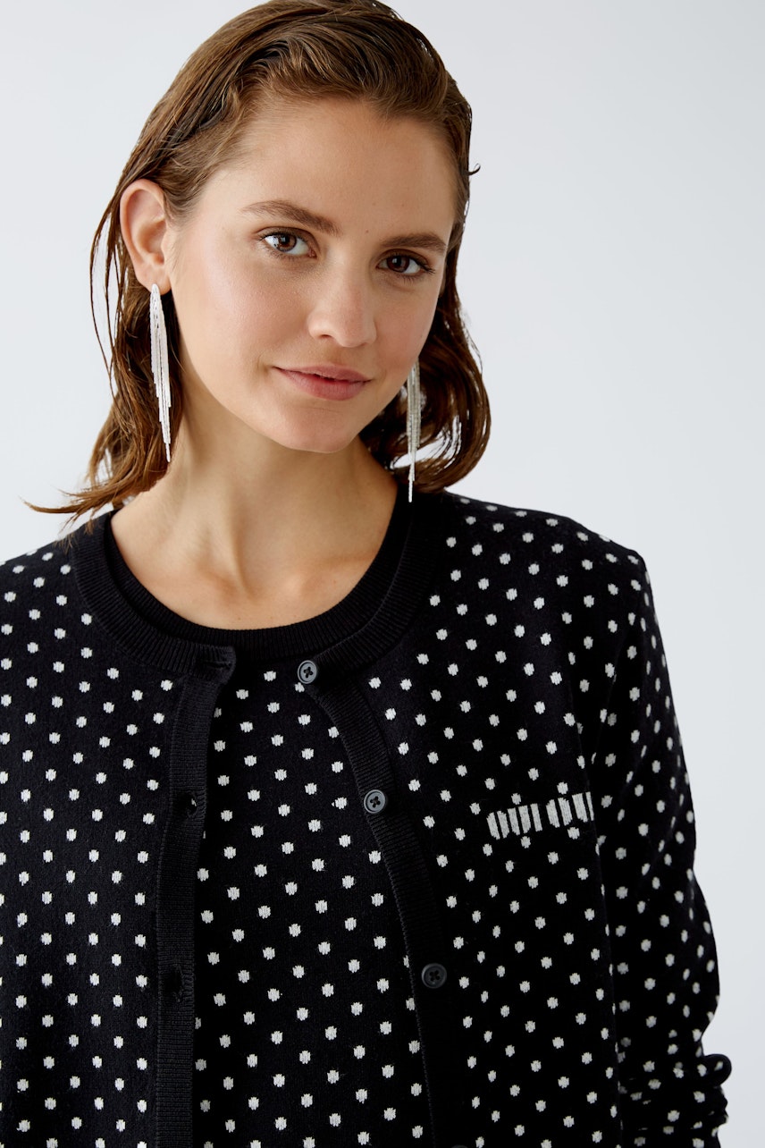 Chic women's cardigan: A woman in a black polka dot cardigan with a stylish design.