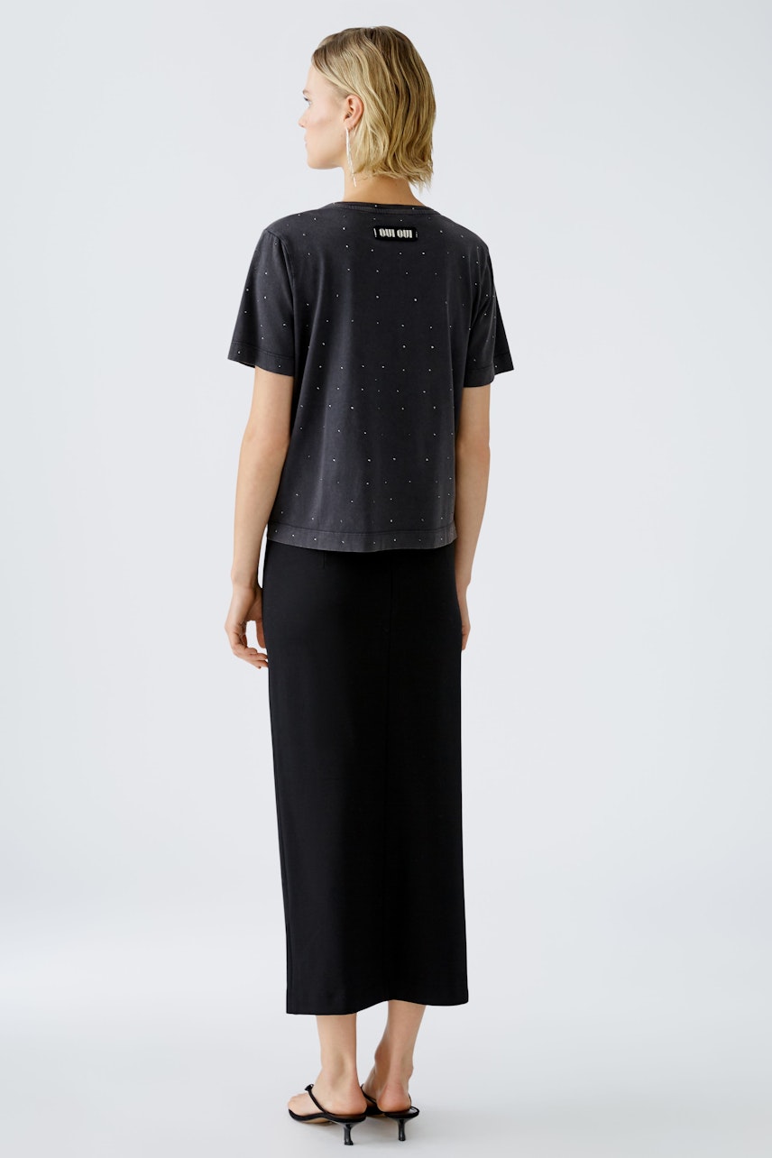 Stylish women's T-shirt: A woman in a black T-shirt with subtle embellishments, exuding casual elegance.