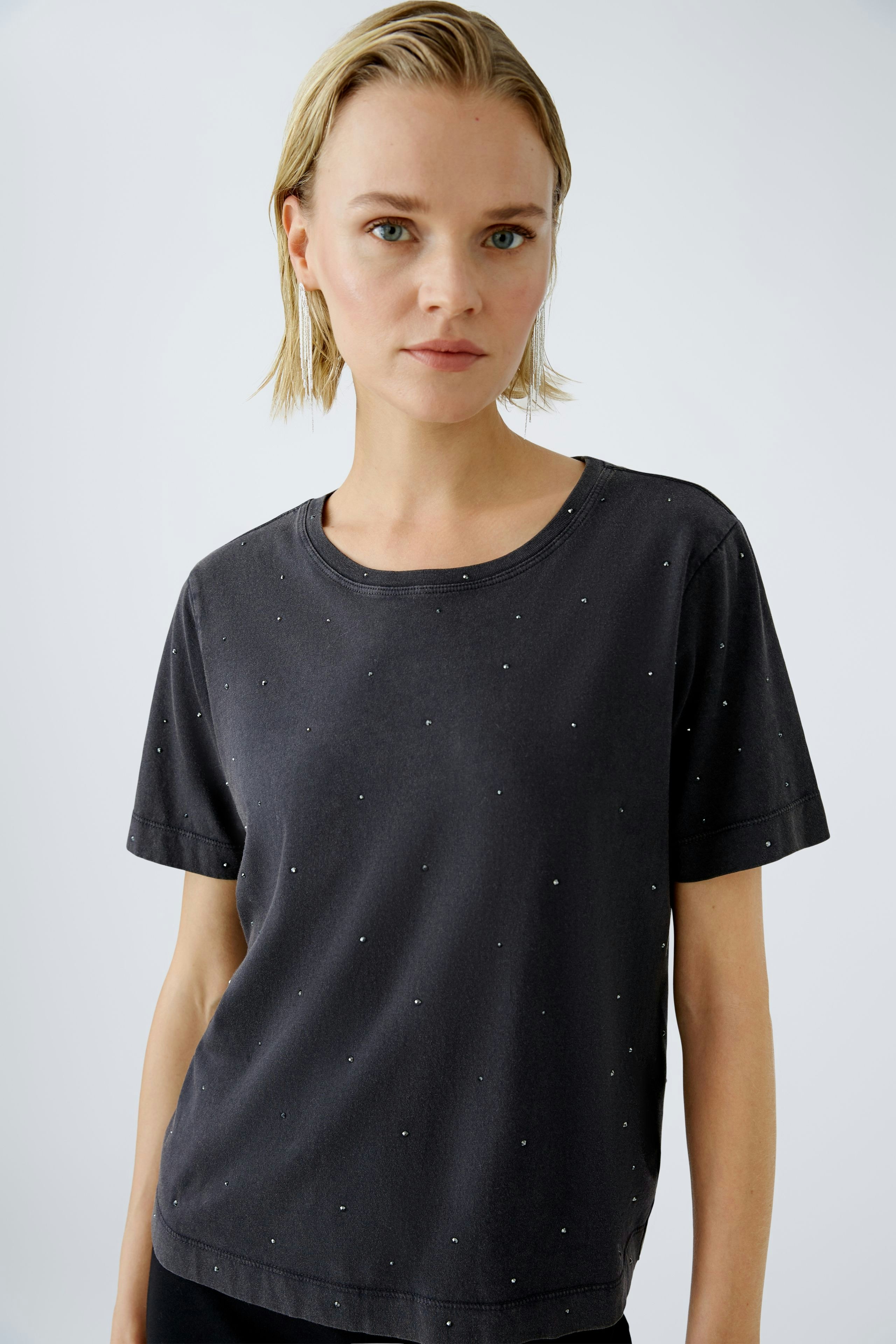 Stylish women's T-shirt: A woman in a black tee adorned with subtle embellishments, exuding casual elegance.