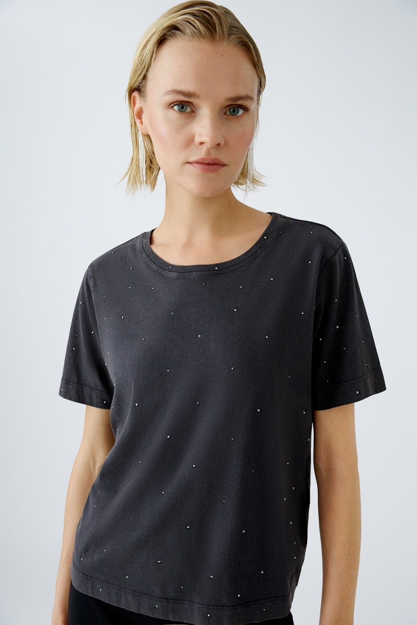 Stylish women's T-shirt: A woman in a black tee adorned with subtle embellishments, exuding casual elegance.