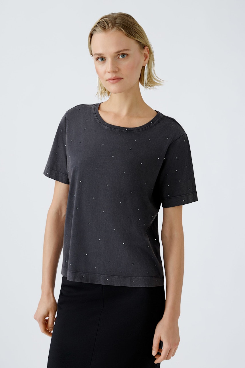 Stylish women's T-shirt: Woman in a dark tee with subtle embellishments, exuding casual elegance.