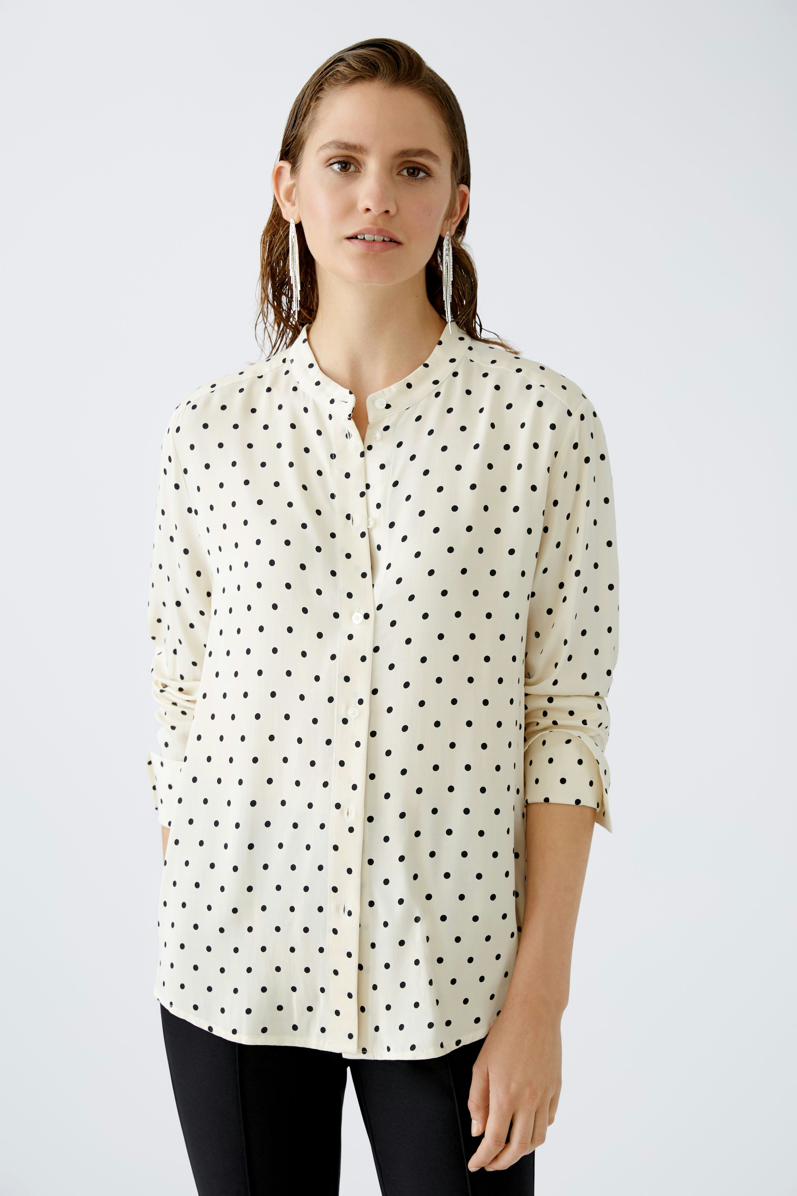 Elegant women's blouse: A woman in a cream blouse with black polka dots, exuding a chic style.